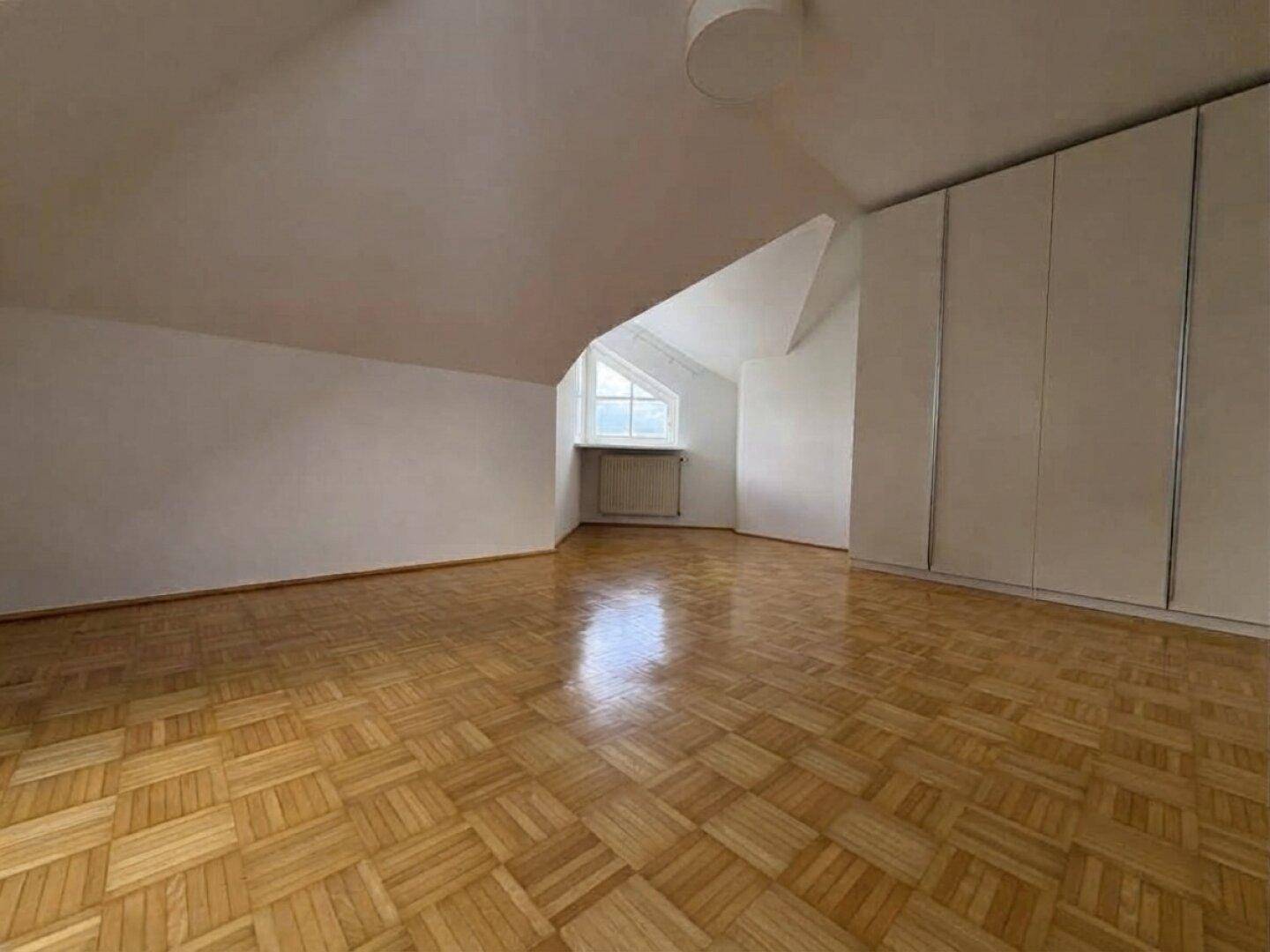 Geräumiges Schlafzimmer mit Parkettboden, Einbauschrank und Dachschrägen.
