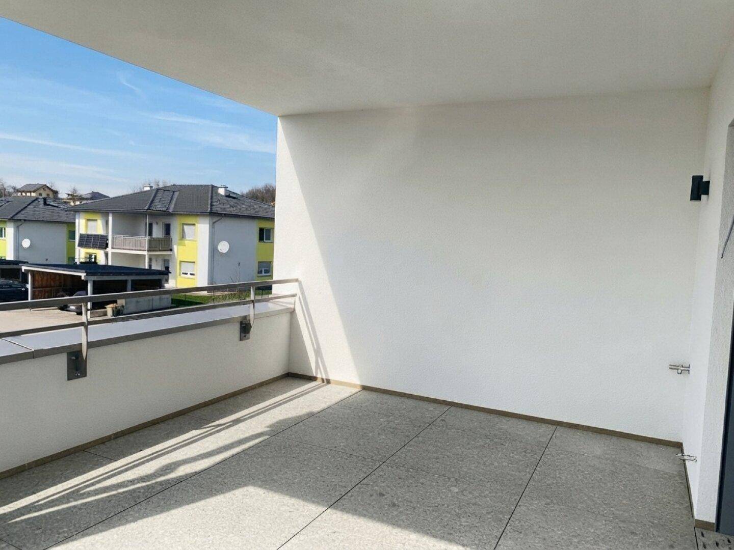 Heller Balkon mit modernem Fliesenboden und Blick auf die umliegenden Gebäude.