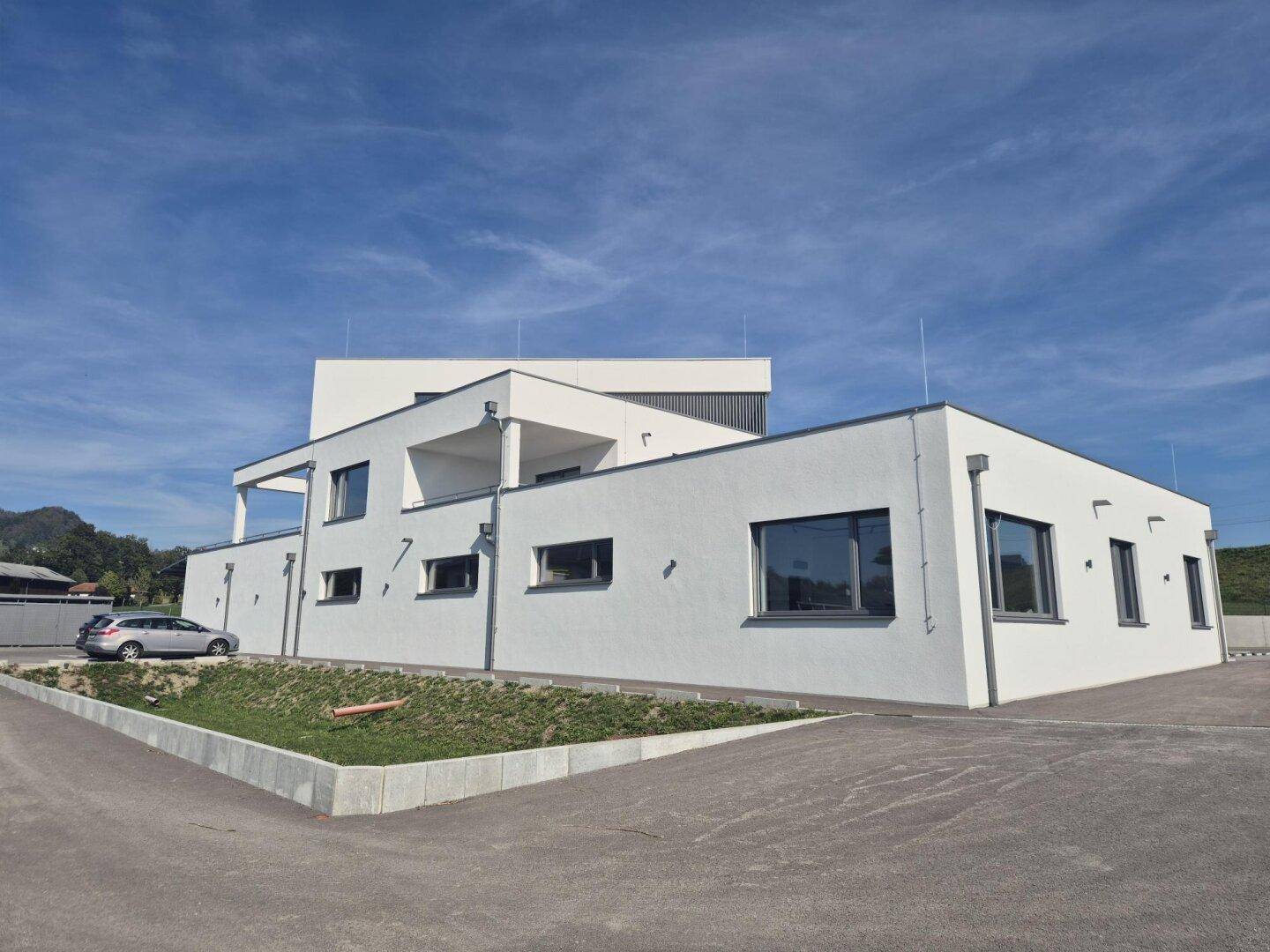 Moderne Architektur des Neubaus mit klaren Linien und großen Fenstern in ländlicher Umgebung.