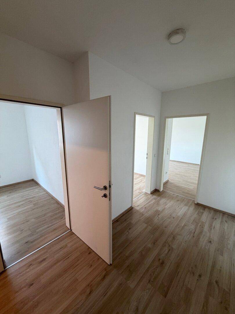 Heller Flur mit Laminatboden und mehreren Türen, die zu verschiedenen Räumen führen.
