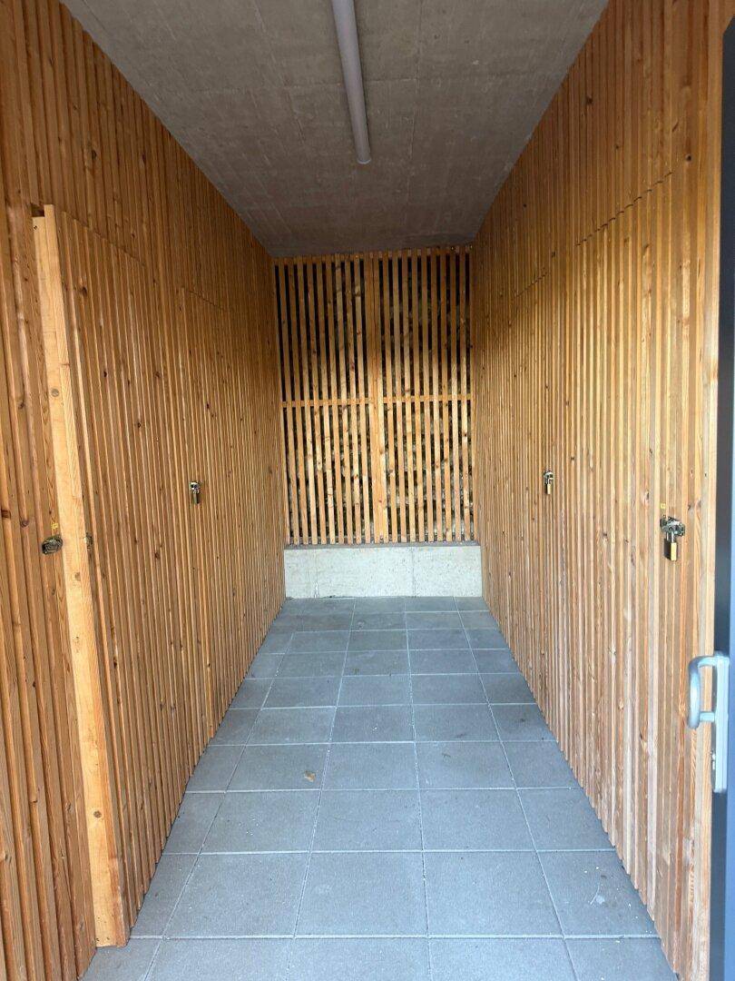 Langer Lagerraum mit Holzlattenwänden und Fliesenboden, ideal für zusätzlichen Stauraum.