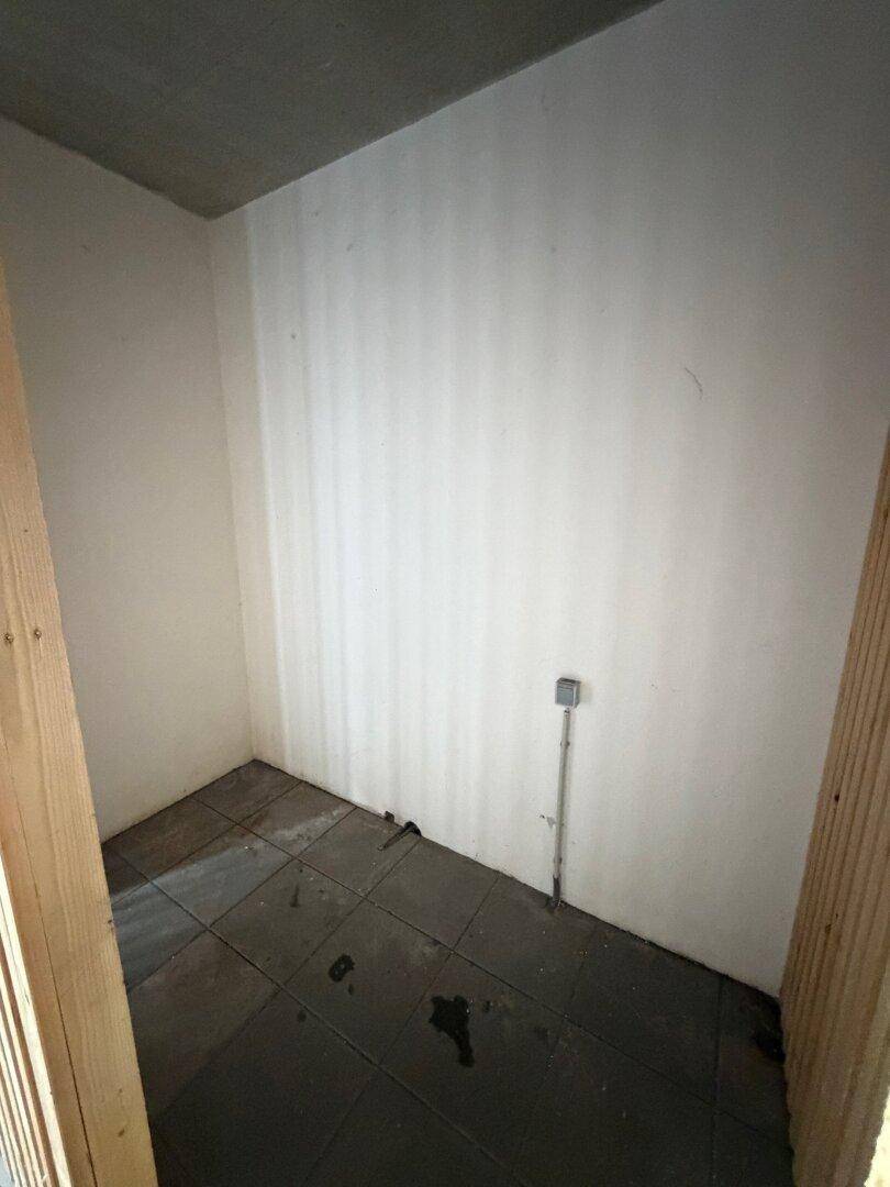 Kleiner Abstellraum mit weißen Wänden und Fliesenboden, bietet praktischen Stauraum.