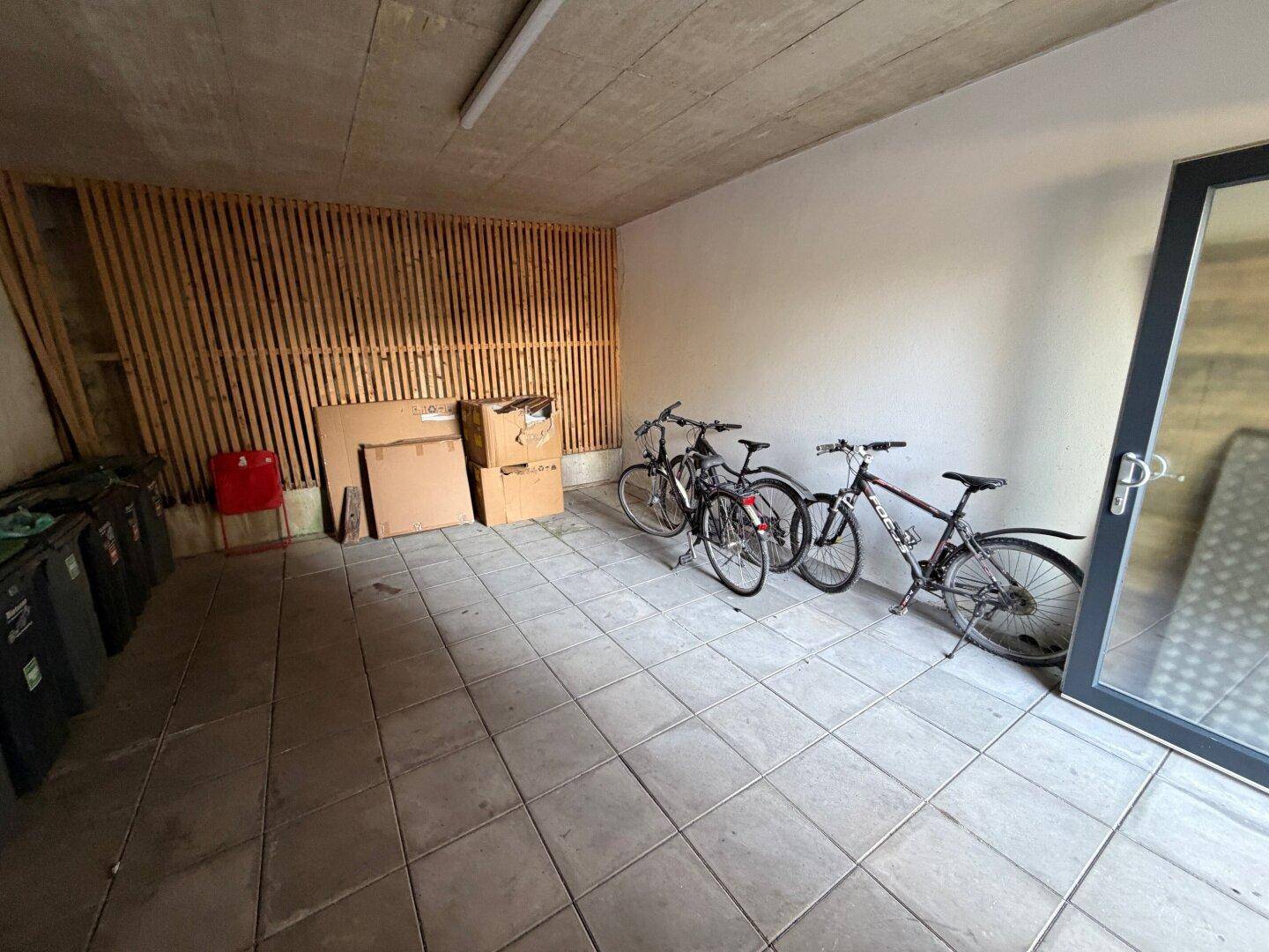 Fahrradraum mit Fliesenboden und Holzlattenwand, bietet sicheren Platz für Fahrräder.