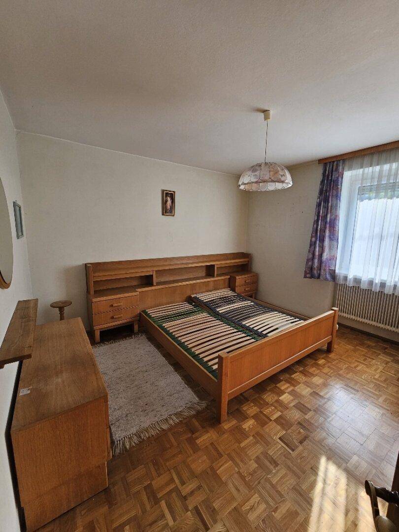 Schlafzimmer mit Doppelbett, Holzmöbeln und Parkettboden.