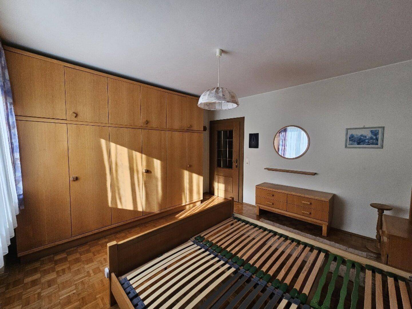 Schlafzimmer mit Einbauschränken, Doppelbett und Parkettboden.