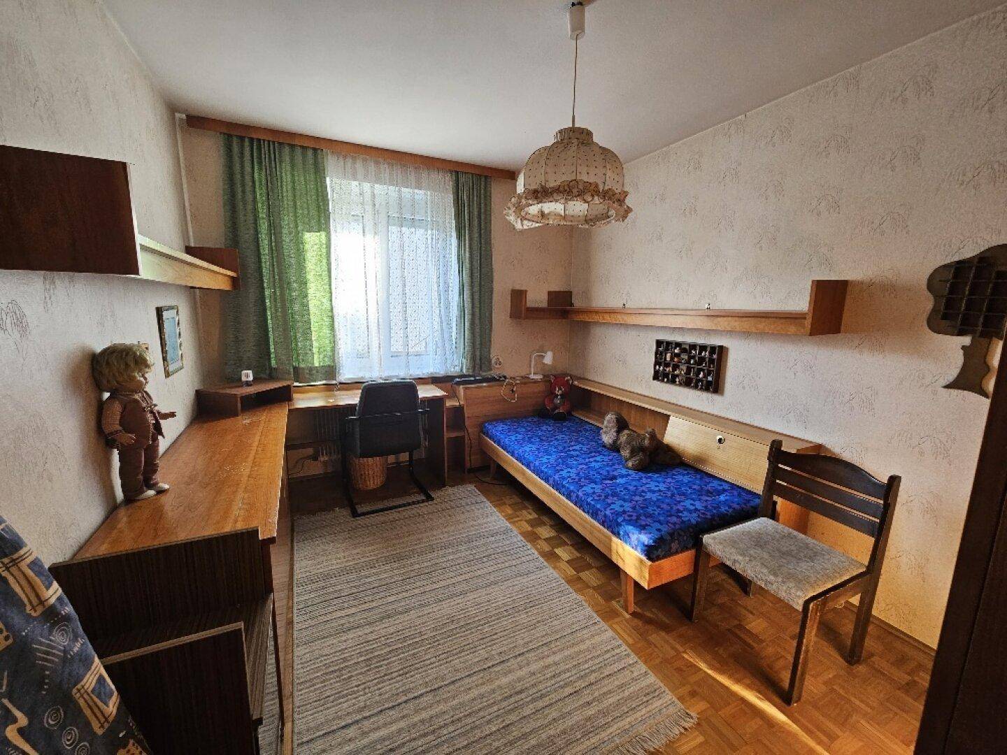 Kinderzimmer mit Einzelbett, Schreibtisch und Holzmöbeln.