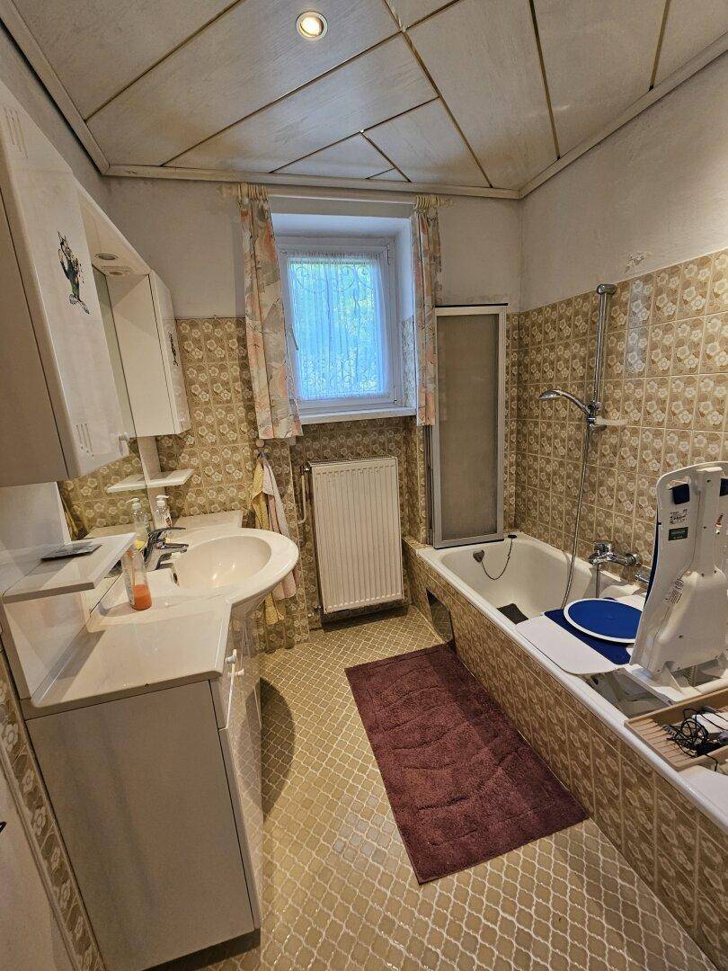 Badezimmer mit Badewanne, Waschbecken und Fliesen im 80er-Jahre-Stil.