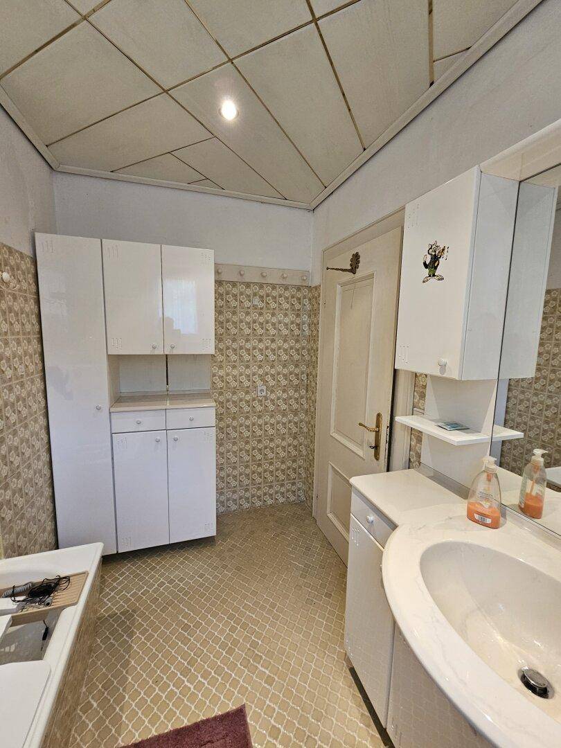 Badezimmer mit weißen Schränken, Waschbecken und gemusterten Fliesen.