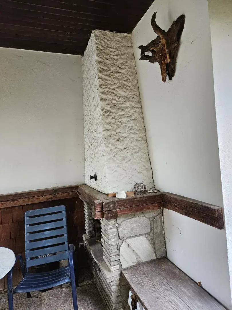 Gemütliche überdachte Terrasse mit rustikalem Kamin, Holzbalken und Sitzgelegenheiten für entspannte Stunden.