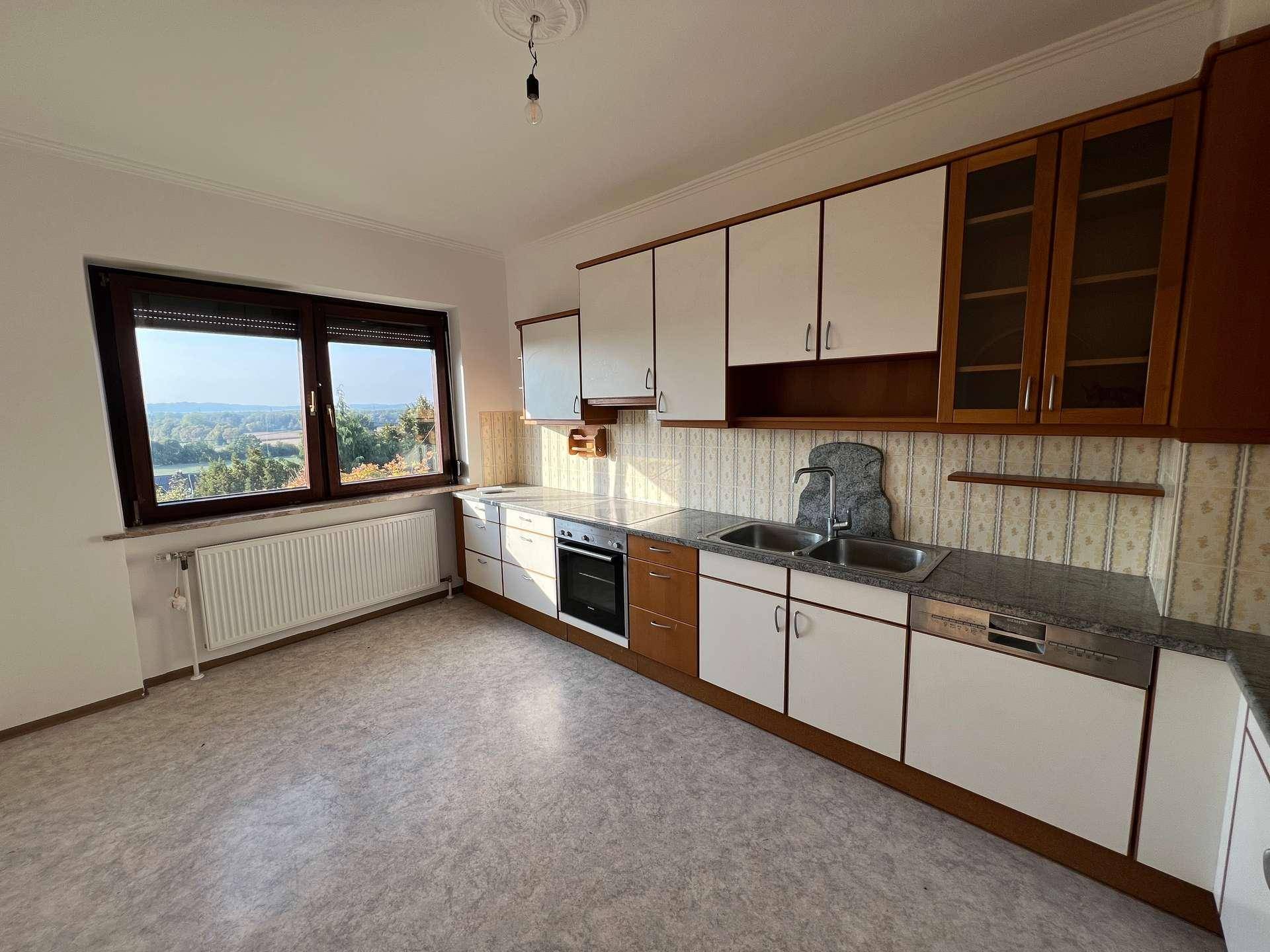 Funktionale Küche mit Einbauschränken, Spüle, Backofen und Geschirrspüler, sowie einem Fenster mit Ausblick.