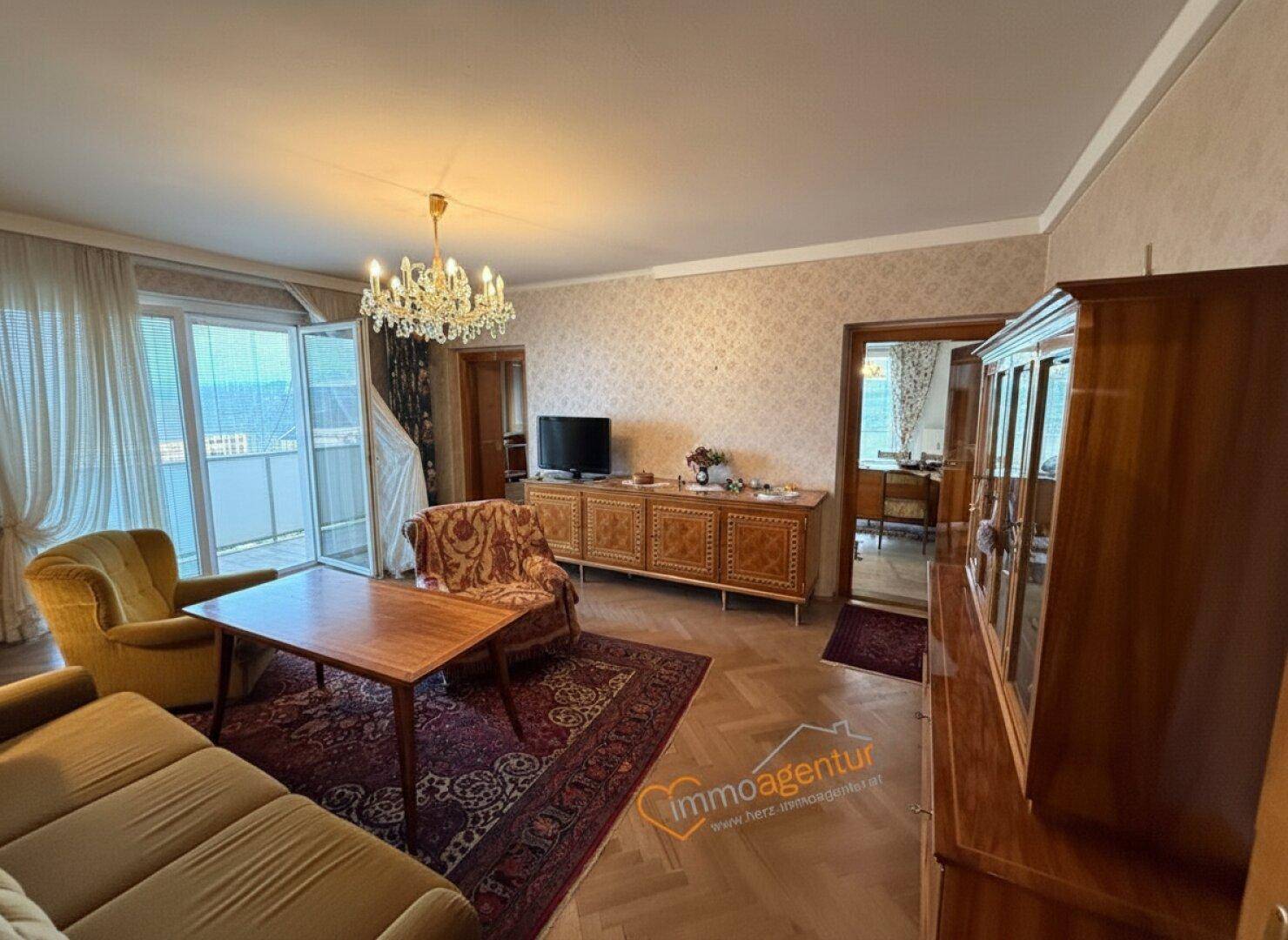 Wohnzimmer mit klassischer Einrichtung, Parkettboden und Zugang zu einem Außenbereich.