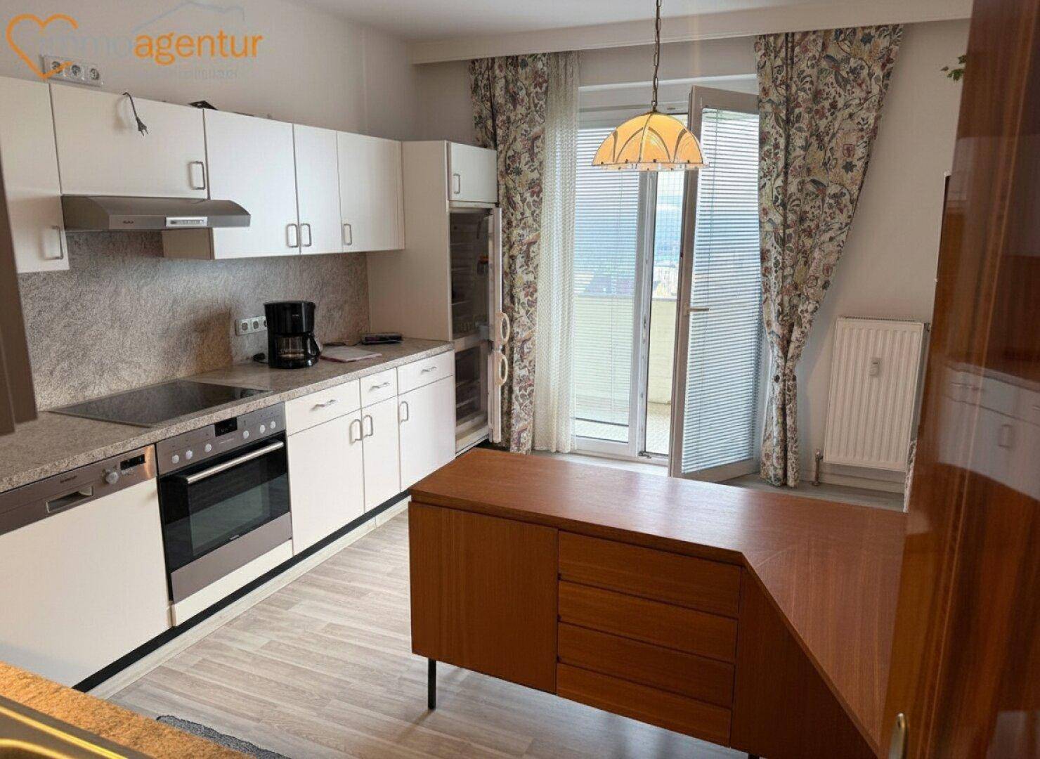 Helle Küche mit weißen Schränken, integrierten Geräten und Zugang zu einem Balkon.