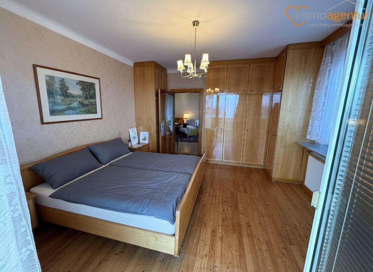 Schlafzimmer mit Doppelbett, Einbauschränken aus Holz und einem Holzboden.