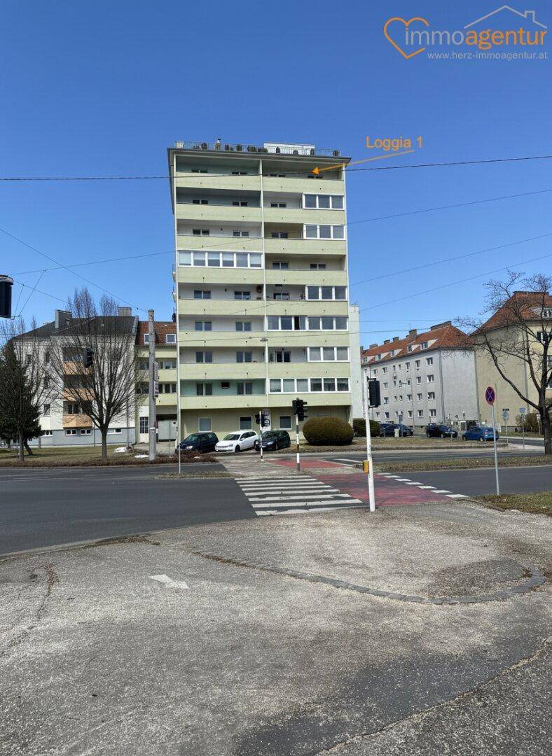 Ansicht des Wohngebäudes von der Straße mit einem Hinweis auf die Loggia im obersten Stockwerk.