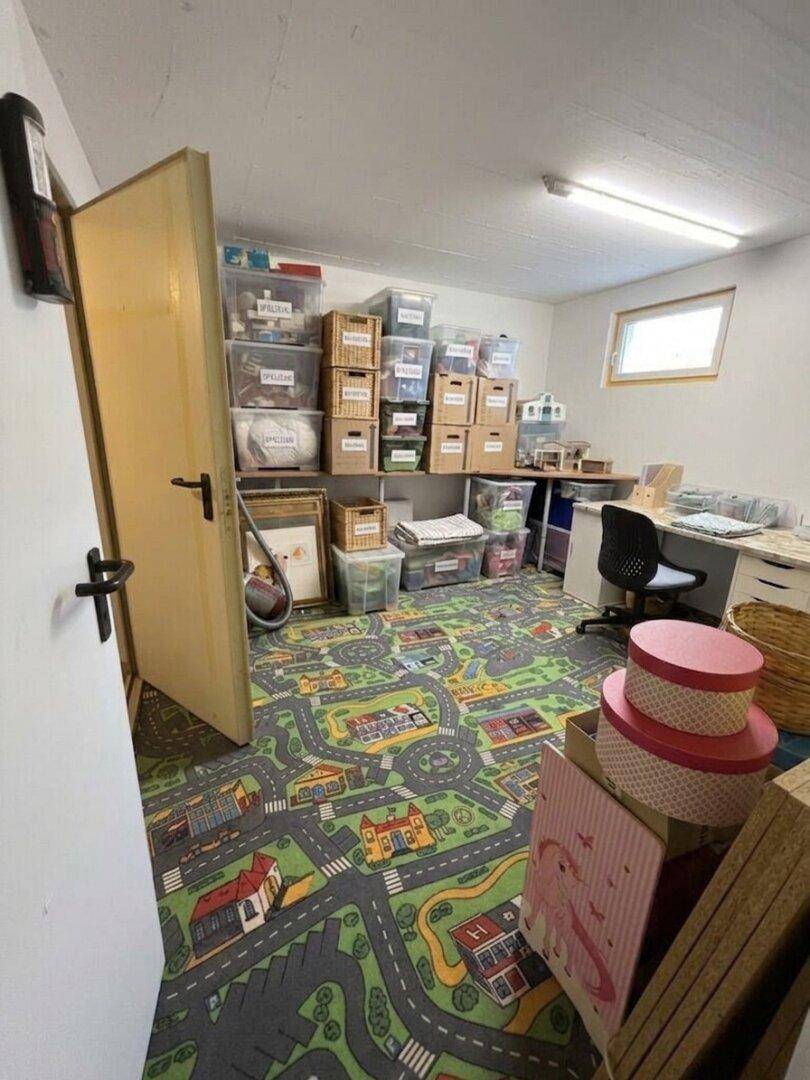 Praktischer Abstellraum im Keller mit Regalen, Lagerboxen und einem bunten Teppich.