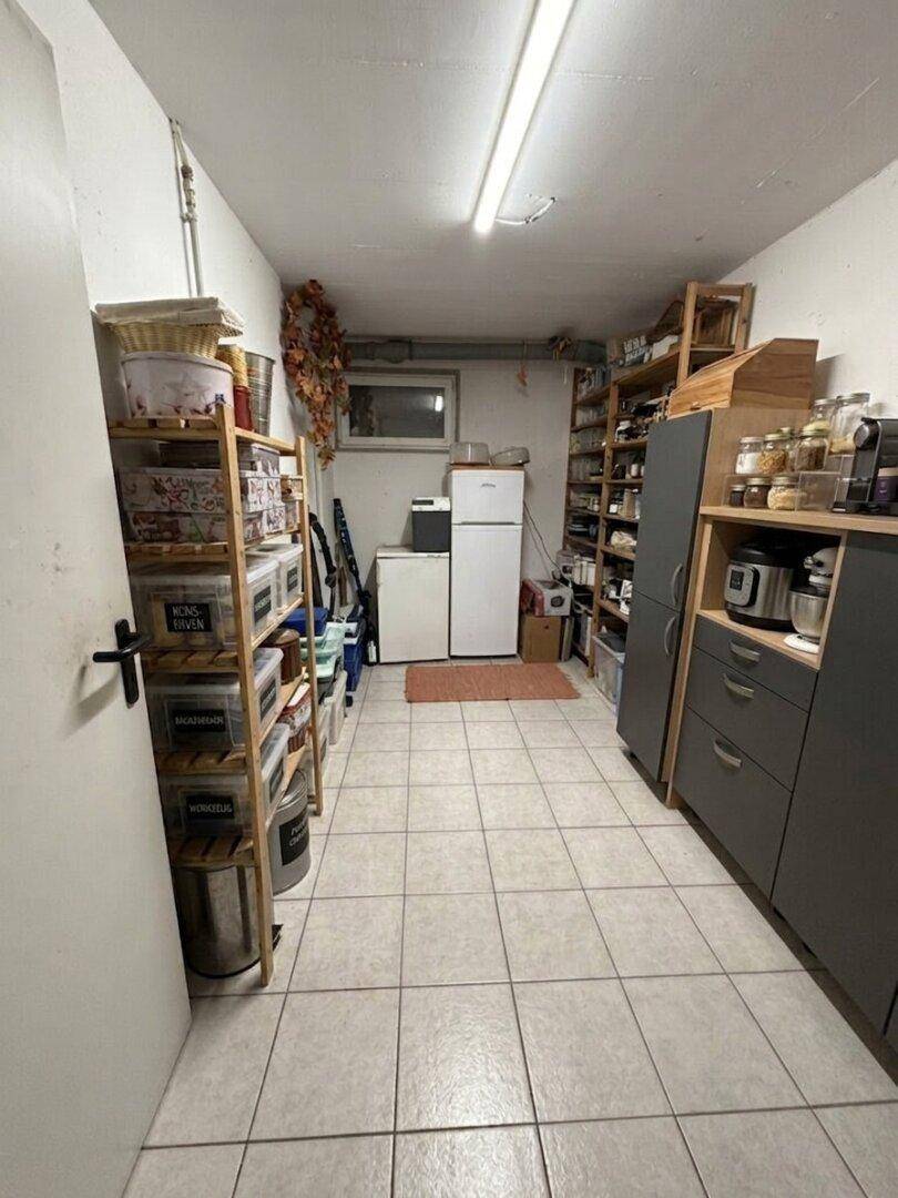 Geräumige Speisekammer im Keller mit Regalen, Fliesenboden und zusätzlichem Kühlschrank.