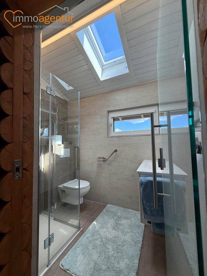 Modernes Badezimmer mit begehbarer Dusche, Wand-WC, Dachfenster und Fenster für Tageslicht.
