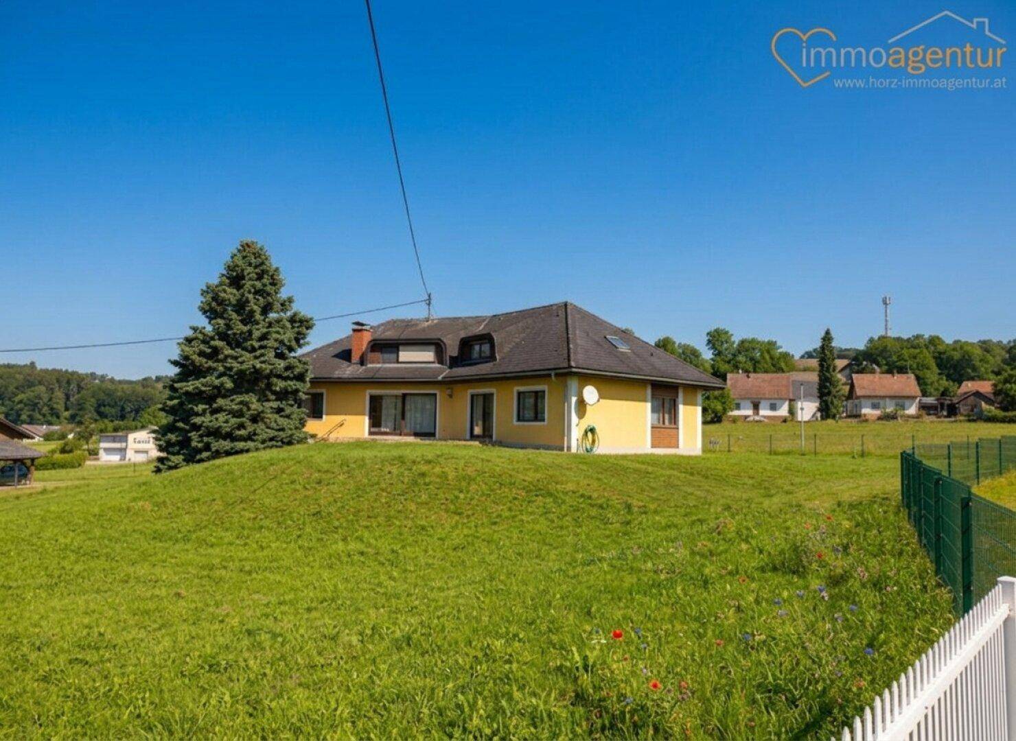 Freistehendes Haus auf einem Hügel mit weitläufiger grüner Wiese und ländlicher Umgebung.