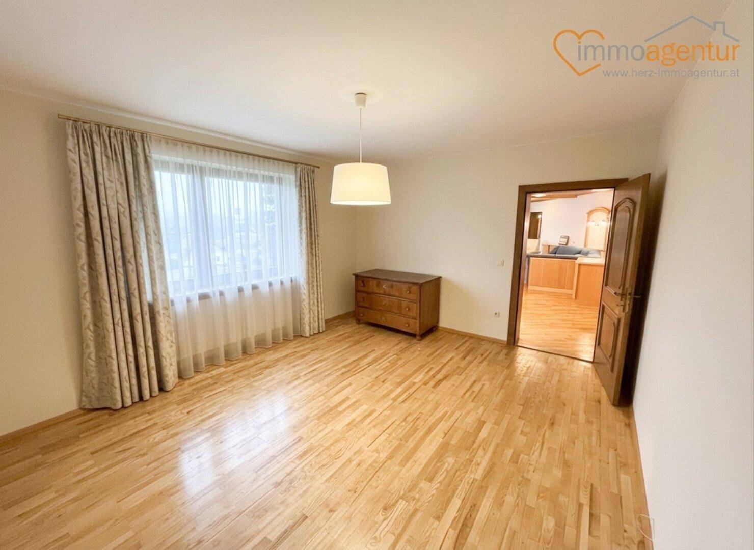 Geräumiges Schlafzimmer mit Holzboden, großen Fenstern und neutralen Wänden.