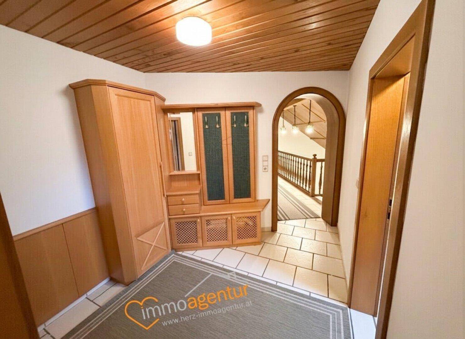 Heller Flur mit Fliesenboden, Holzvertäfelung und Einbauschrank im Landhausstil.