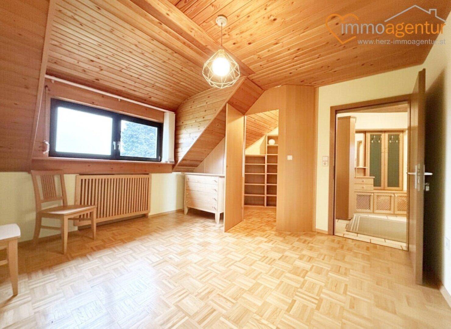Gemütliches Schlafzimmer im Dachgeschoss mit Holzboden, Dachschrägen und Einbauschränken.