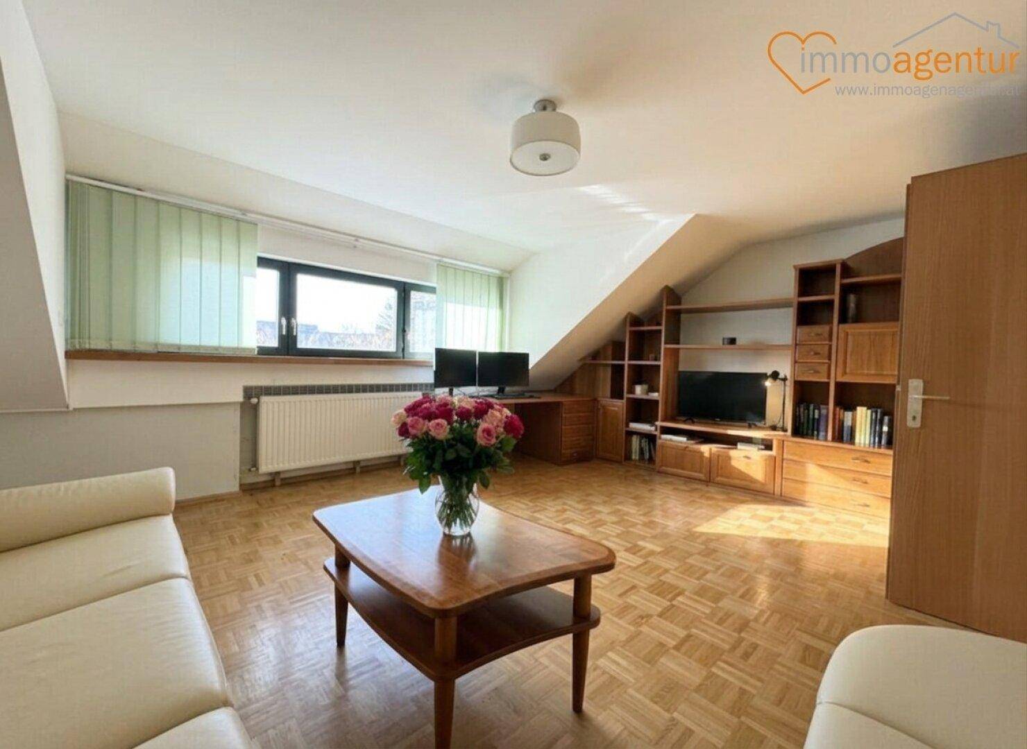 Helles Arbeitszimmer im Dachgeschoss mit Holzboden, Dachschrägen und integrierten Regalen.