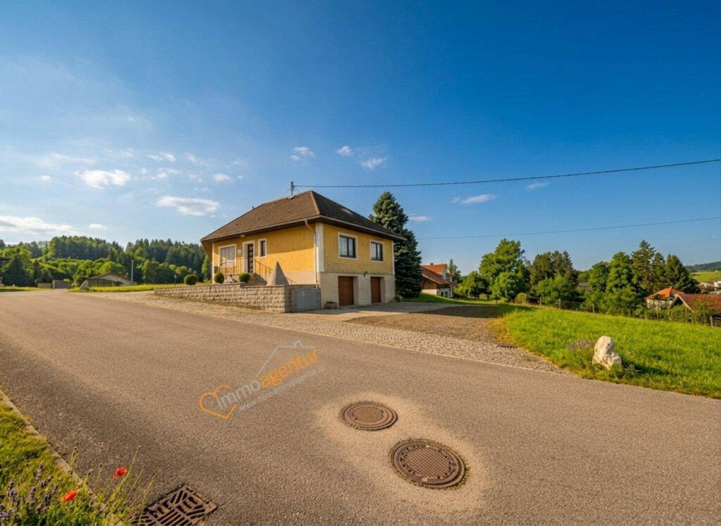Ansicht des Hauses von der Straße, umgeben von grüner Natur und ländlicher Idylle.