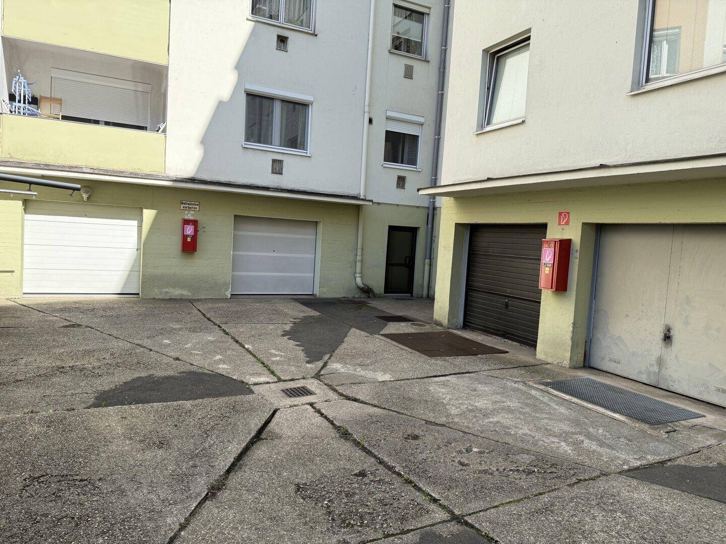 Außenbereich mit mehreren Garagentoren und einem gepflasterten Hof.