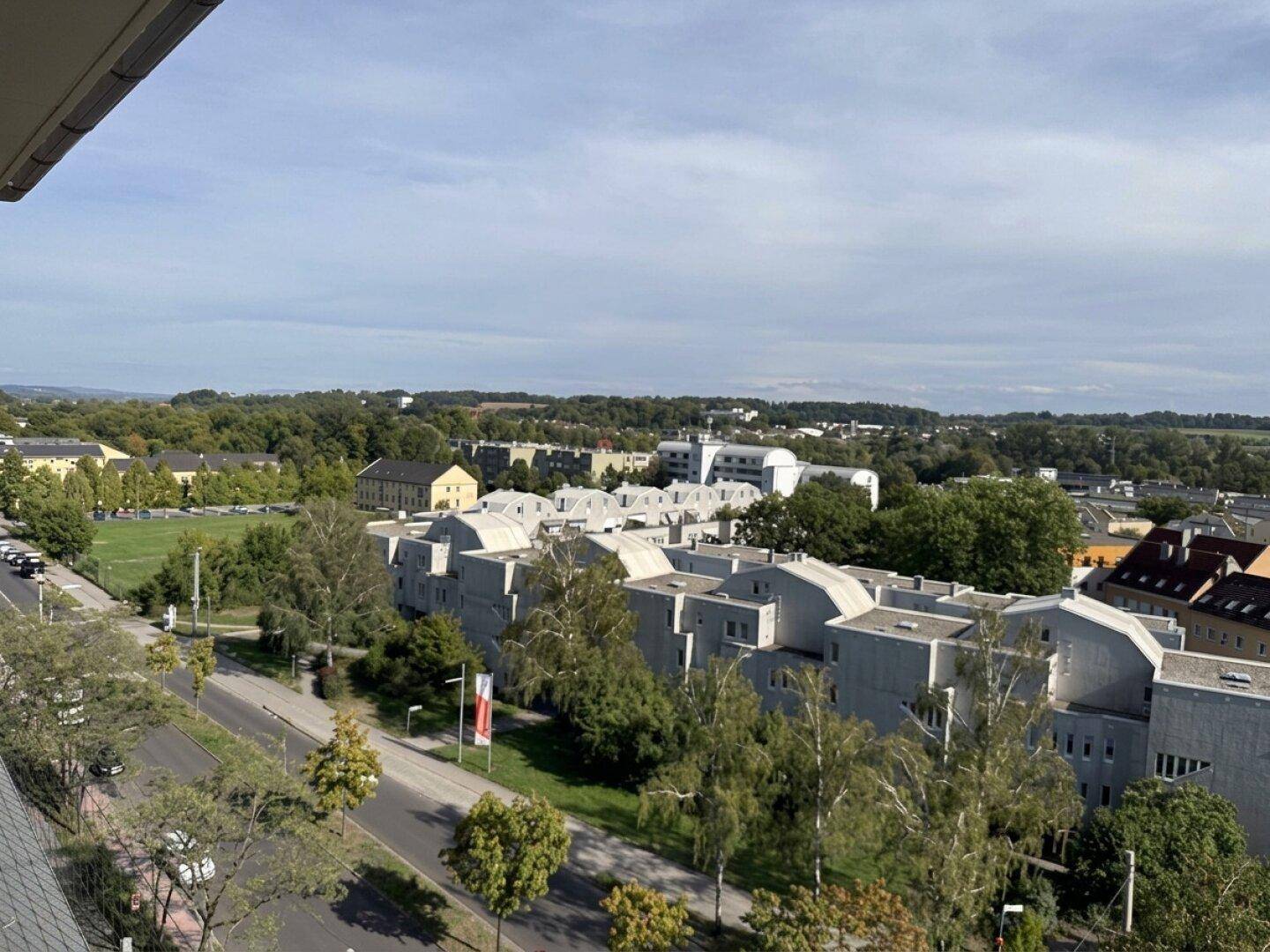 Panoramablick über eine Wohngegend mit modernen Gebäuden, Straßen und viel Grün.