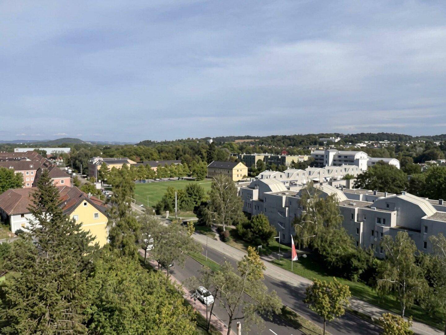 Weitläufiger Ausblick auf eine grüne Wohnsiedlung mit verschiedenen Gebäudetypen und Straßen.