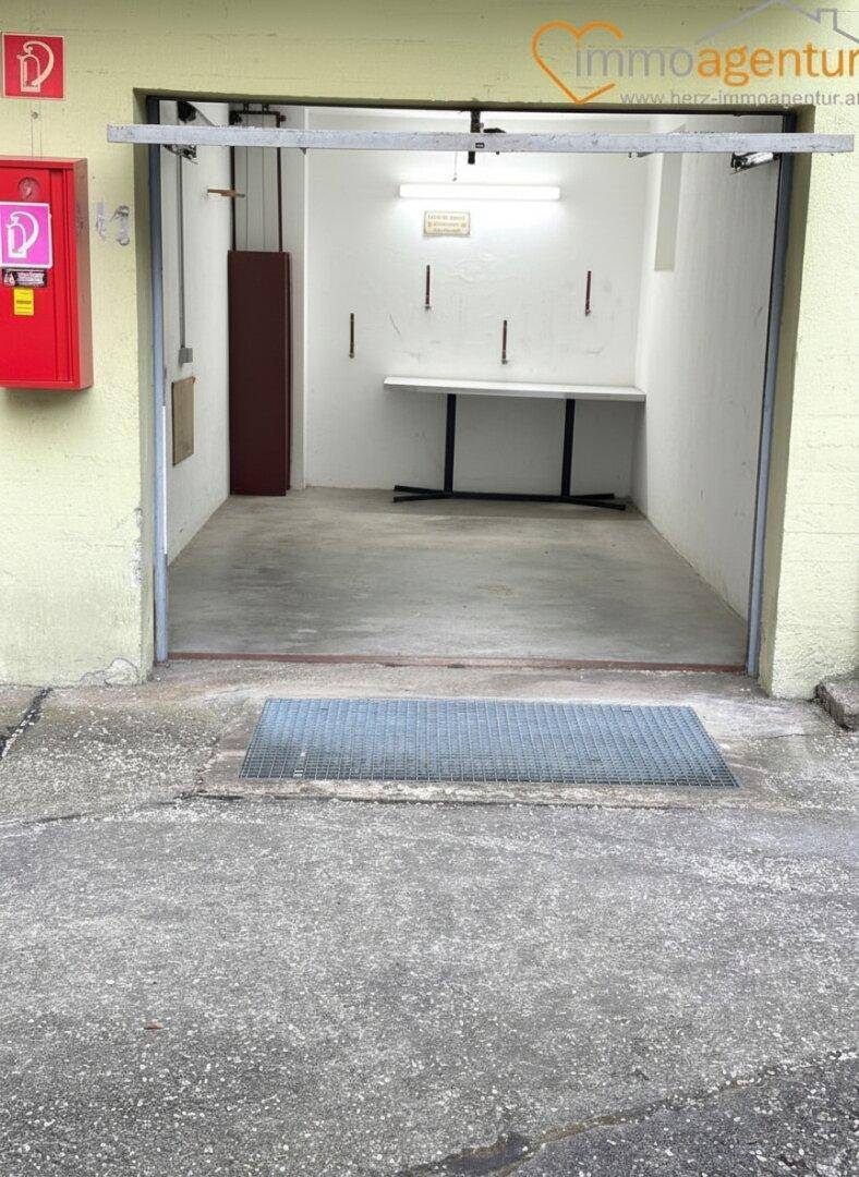 Einzelgarage mit Betonboden und einer einfachen Werkbank an der Rückwand.