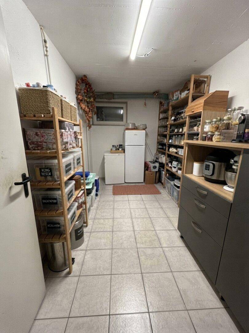 Gut organisierte Speisekammer mit Fliesenboden, Regalen und zusätzlichem Kühlschrank.
