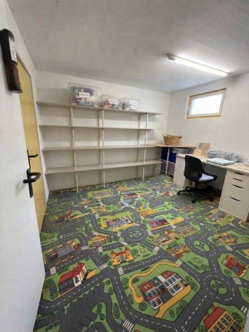 Raum mit spielerischem Straßenmuster-Teppich, Regalen und einem Schreibtisch.