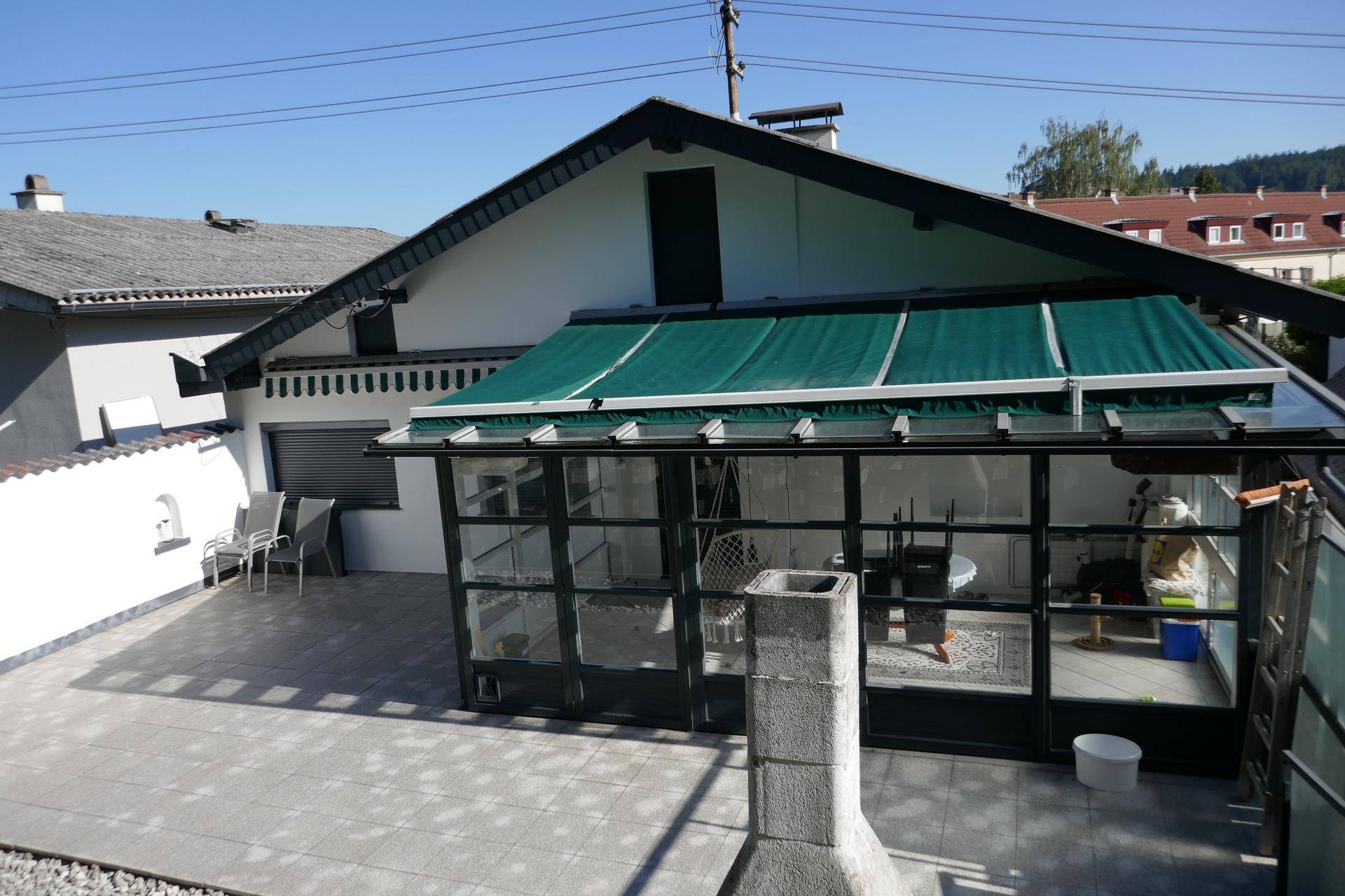 Große geflieste Terrasse mit Wintergarten und Markise, ideal für entspannte Stunden im Freien.