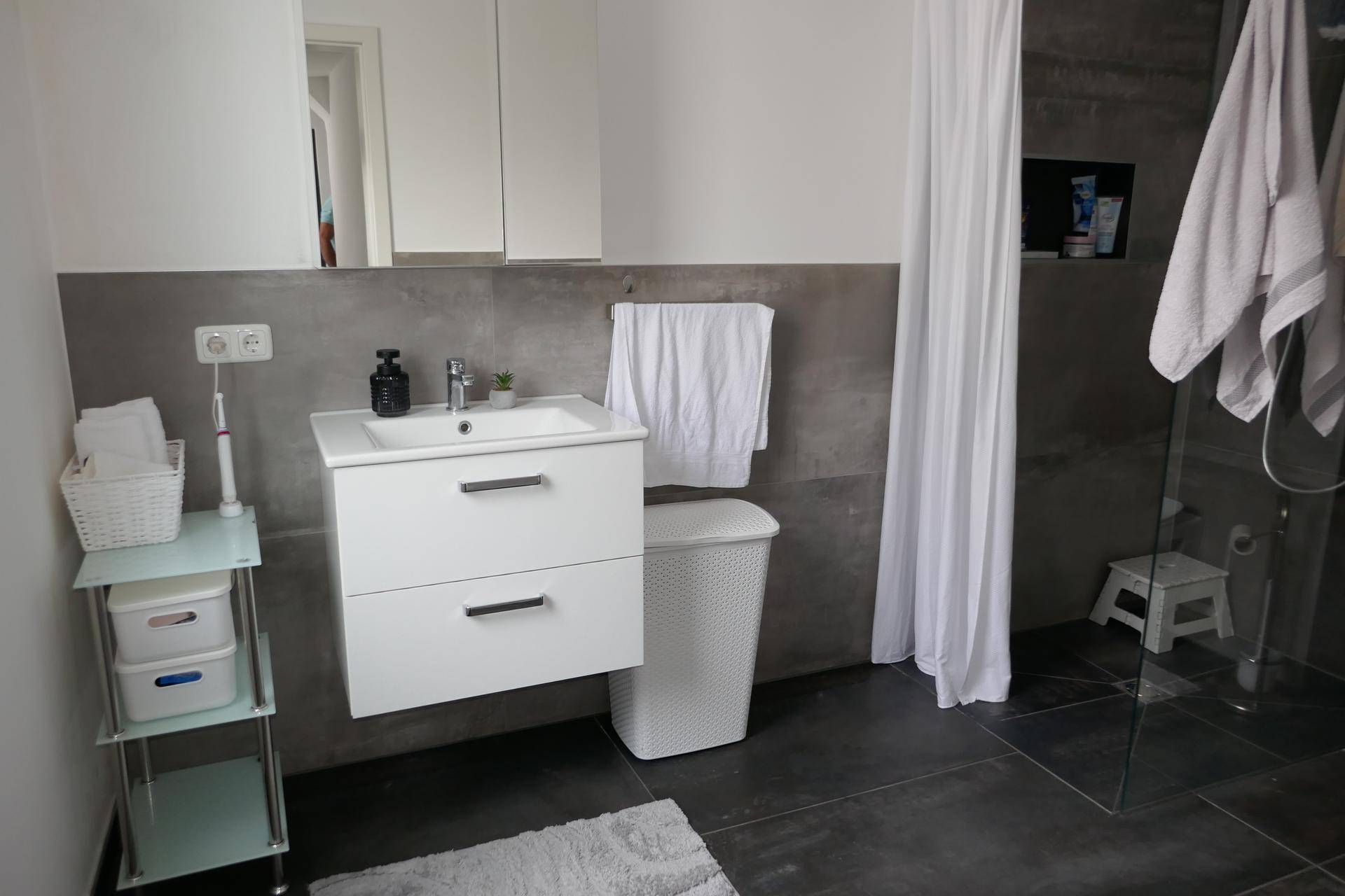 Funktionales Badezimmer mit schwebendem Waschtisch, Dusche und praktischem Stauraum.