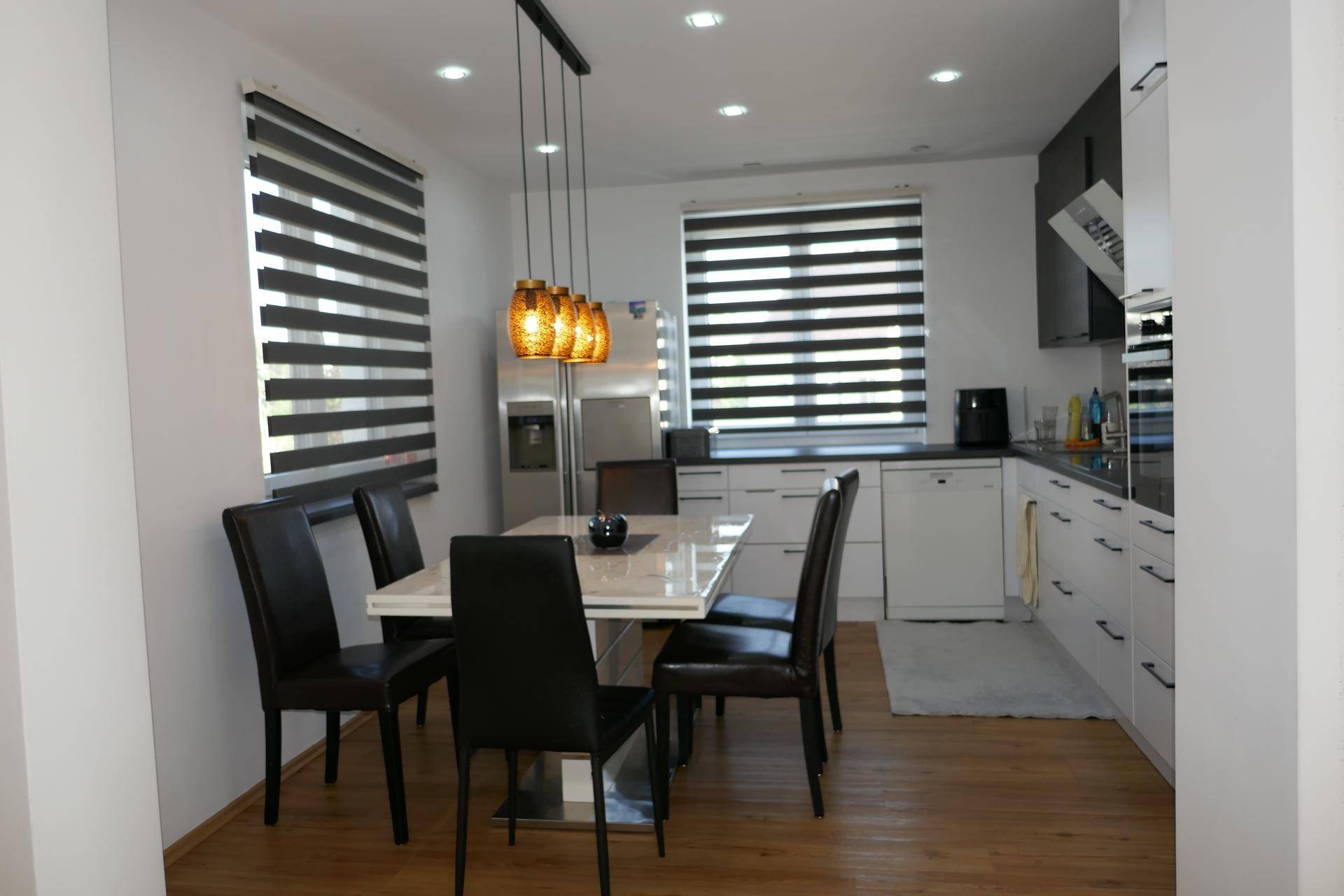 Helle, moderne Küche mit Essbereich, Holzboden und hochwertigen Einbaugeräten.