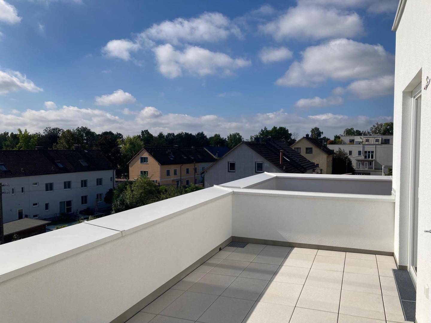 Geräumige Dachterrasse mit hellen Fliesen und hoher Brüstung, bietet einen weiten Blick über die Umgebung.