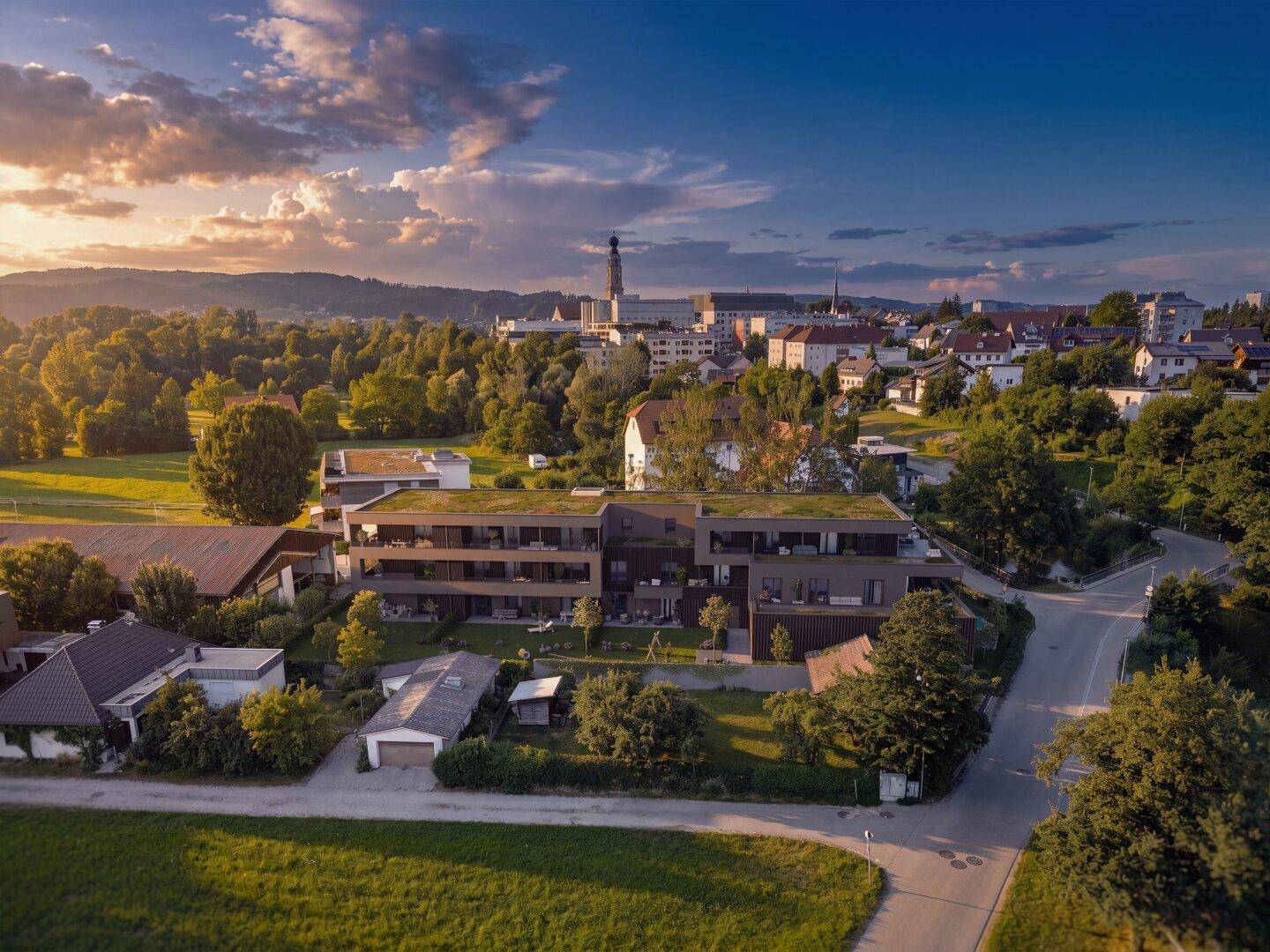 Luftaufnahme der modernen Wohnanlage in grüner Umgebung mit Blick auf die nahegelegene Stadt.