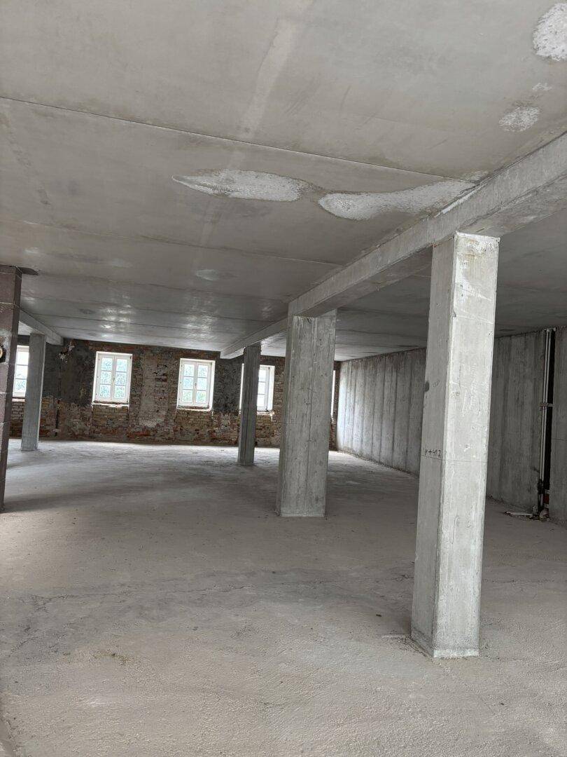 Rohbau eines Innenraums mit Betonstützen und -wänden, bereit für den Ausbau.