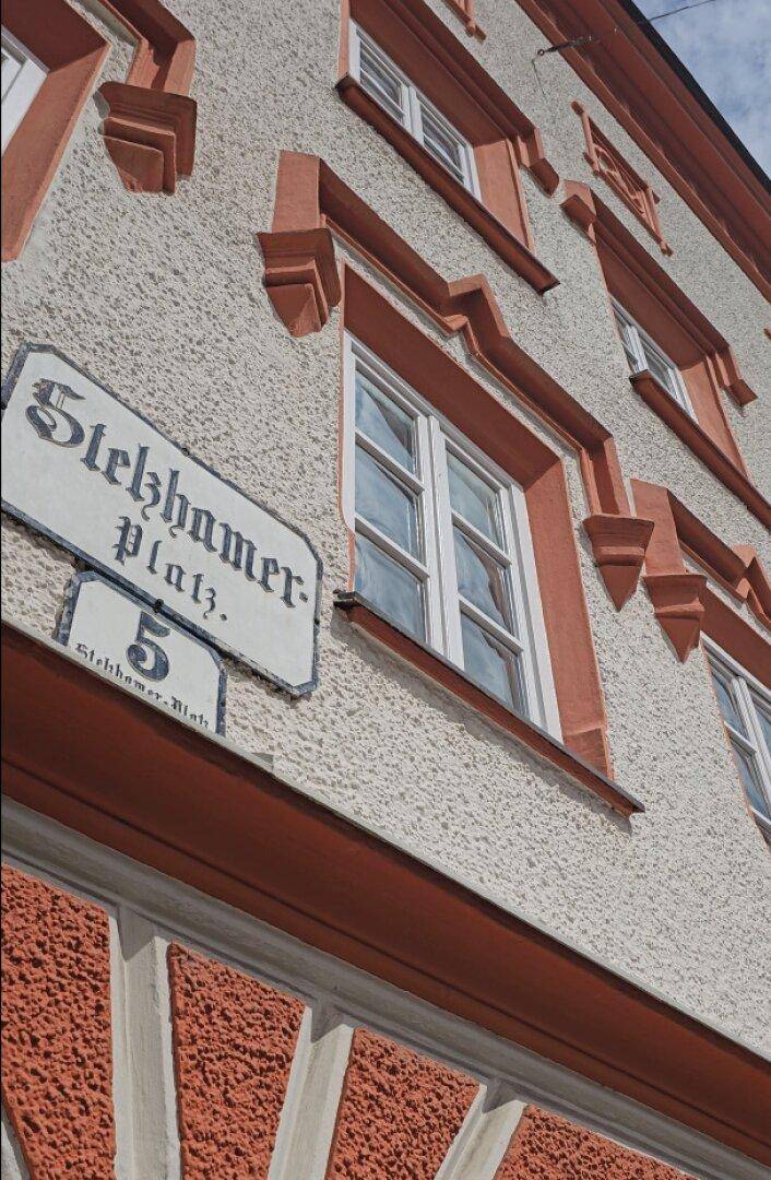 Detailansicht der historischen Fassade mit kunstvollen Fensterrahmen und Straßenschild.