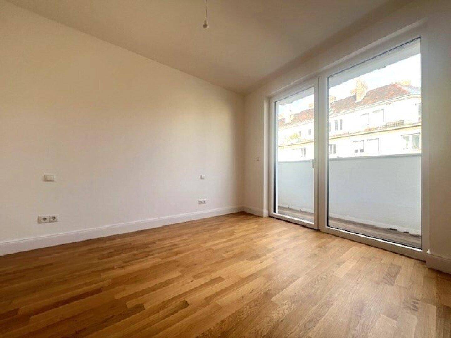 Geräumiges, helles Zimmer mit Parkettboden und großem Balkonzugang, ideal für individuelle Gestaltung.