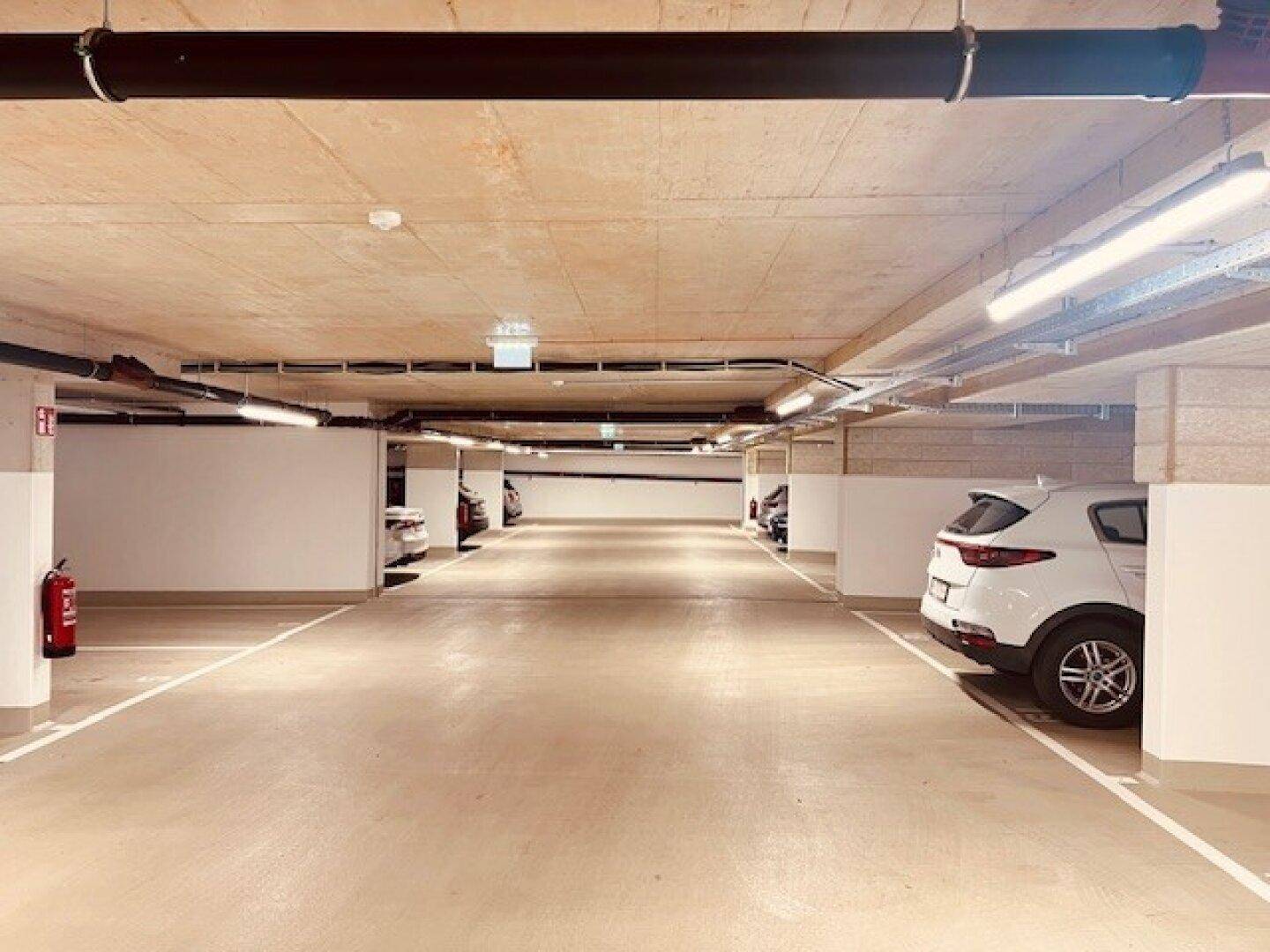 Geräumige Tiefgarage mit markierten Stellplätzen und guter Beleuchtung für Fahrzeuge.