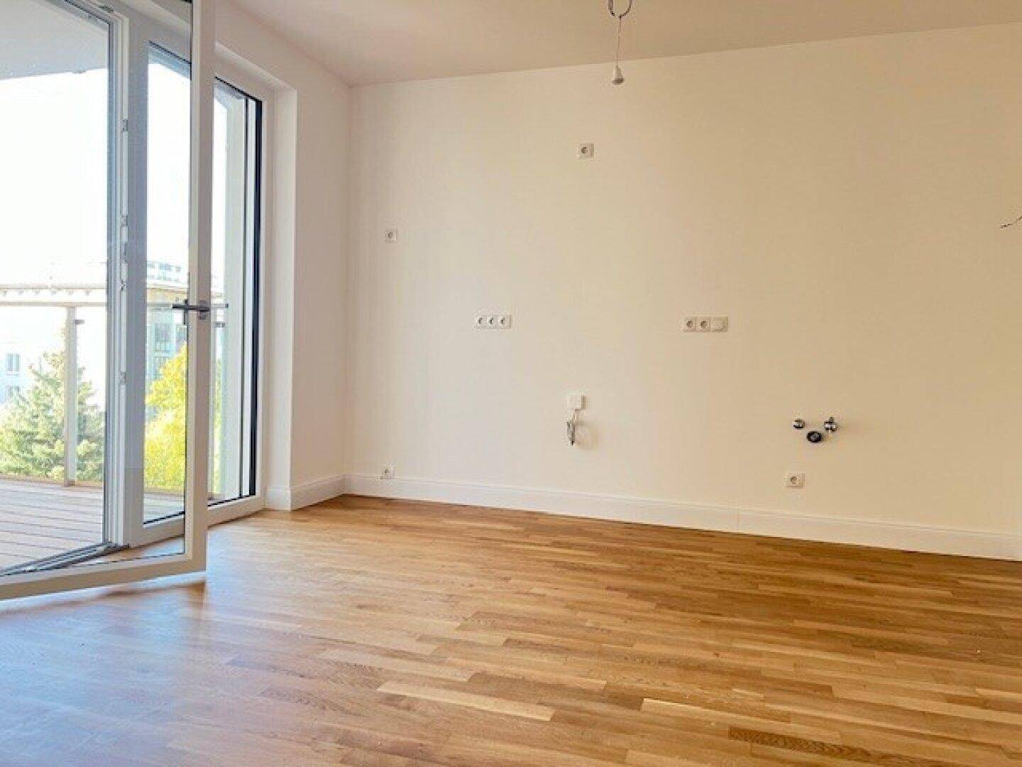 Heller, leerer Raum mit Holzboden und Zugang zu einem Balkon, ideal für individuelle Nutzung.