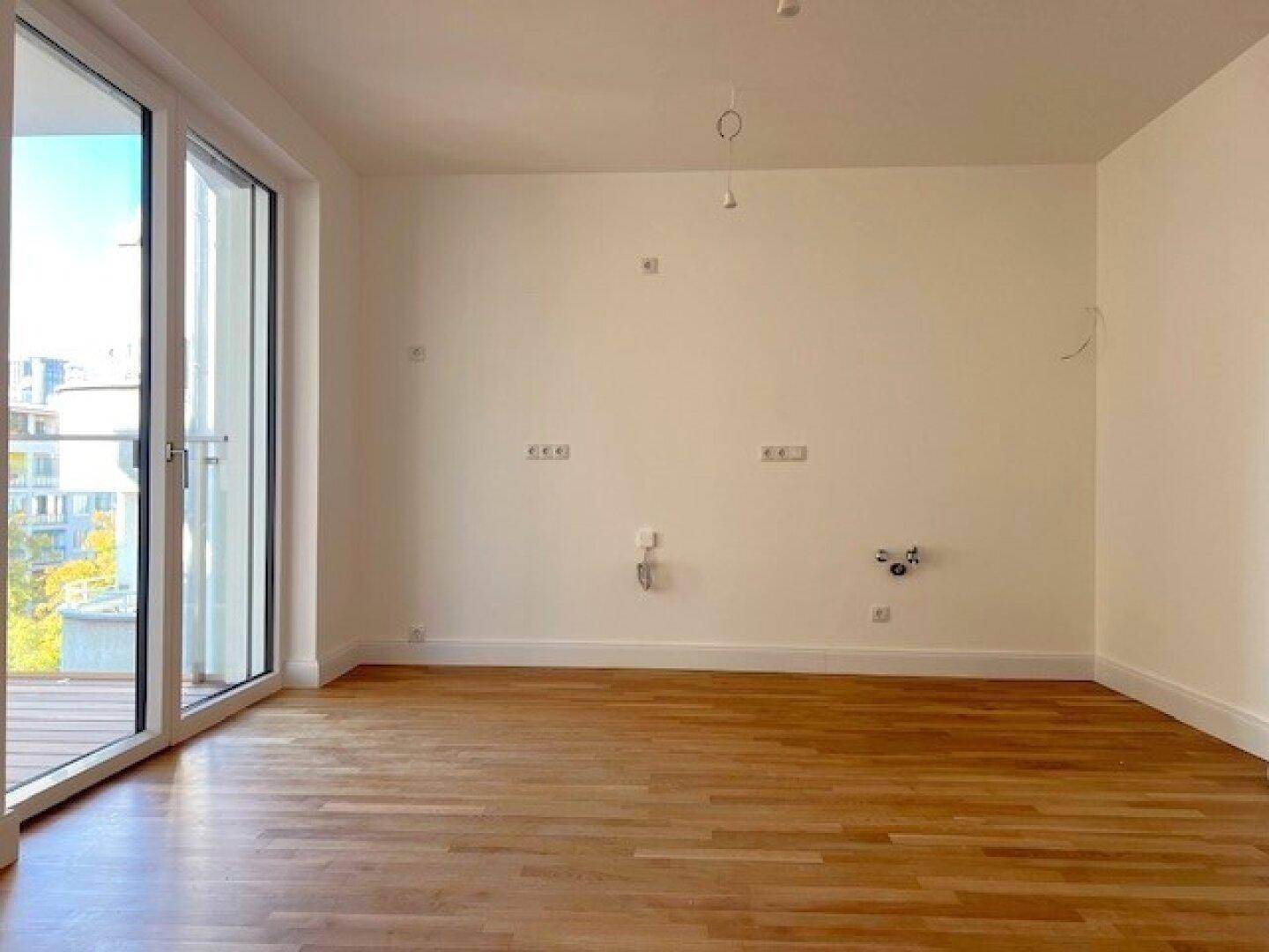 Leerer Raum mit Holzboden und Anschlussmöglichkeiten, bereit für die individuelle Gestaltung.