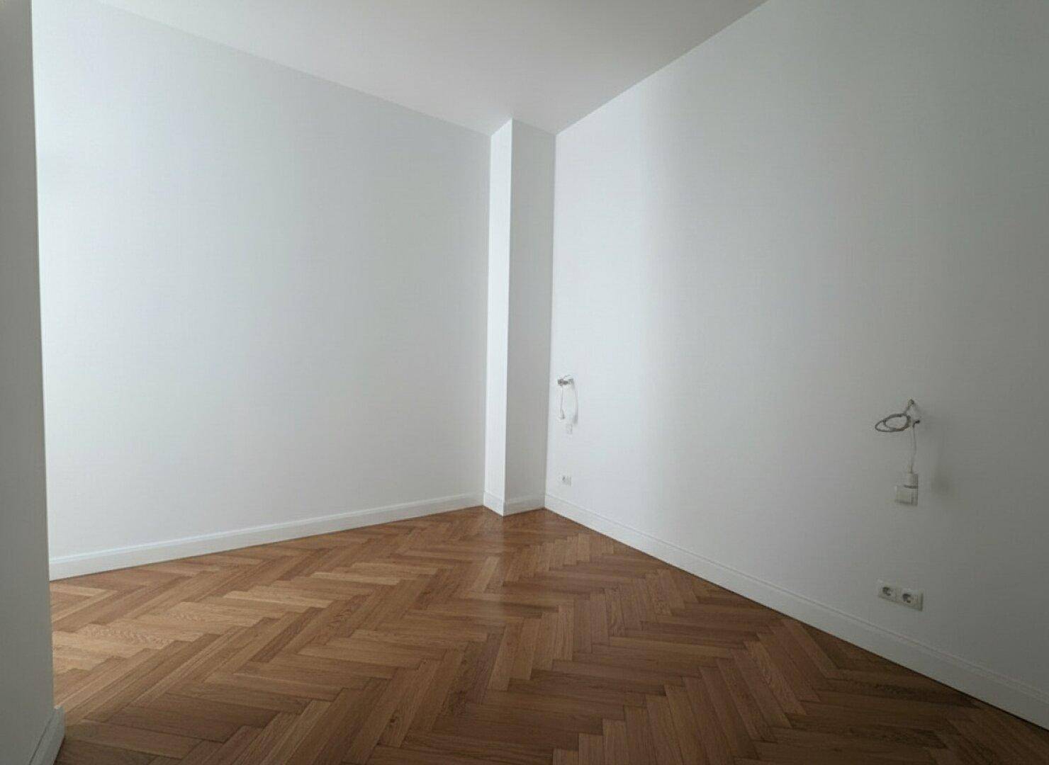 Schlichter, heller Raum mit Fischgrätparkett und weißen Wänden, ideal für individuelle Gestaltung.