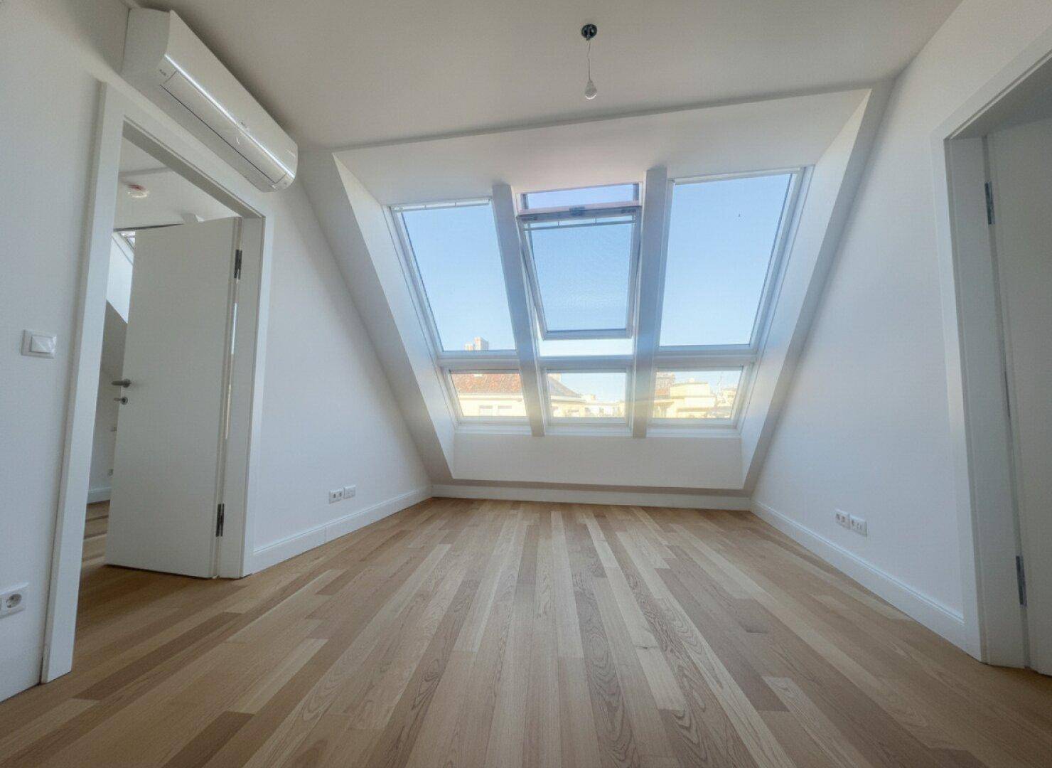Helles Dachgeschosszimmer mit großen Dachfenstern und Holzboden, bereit zur individuellen Gestaltung.