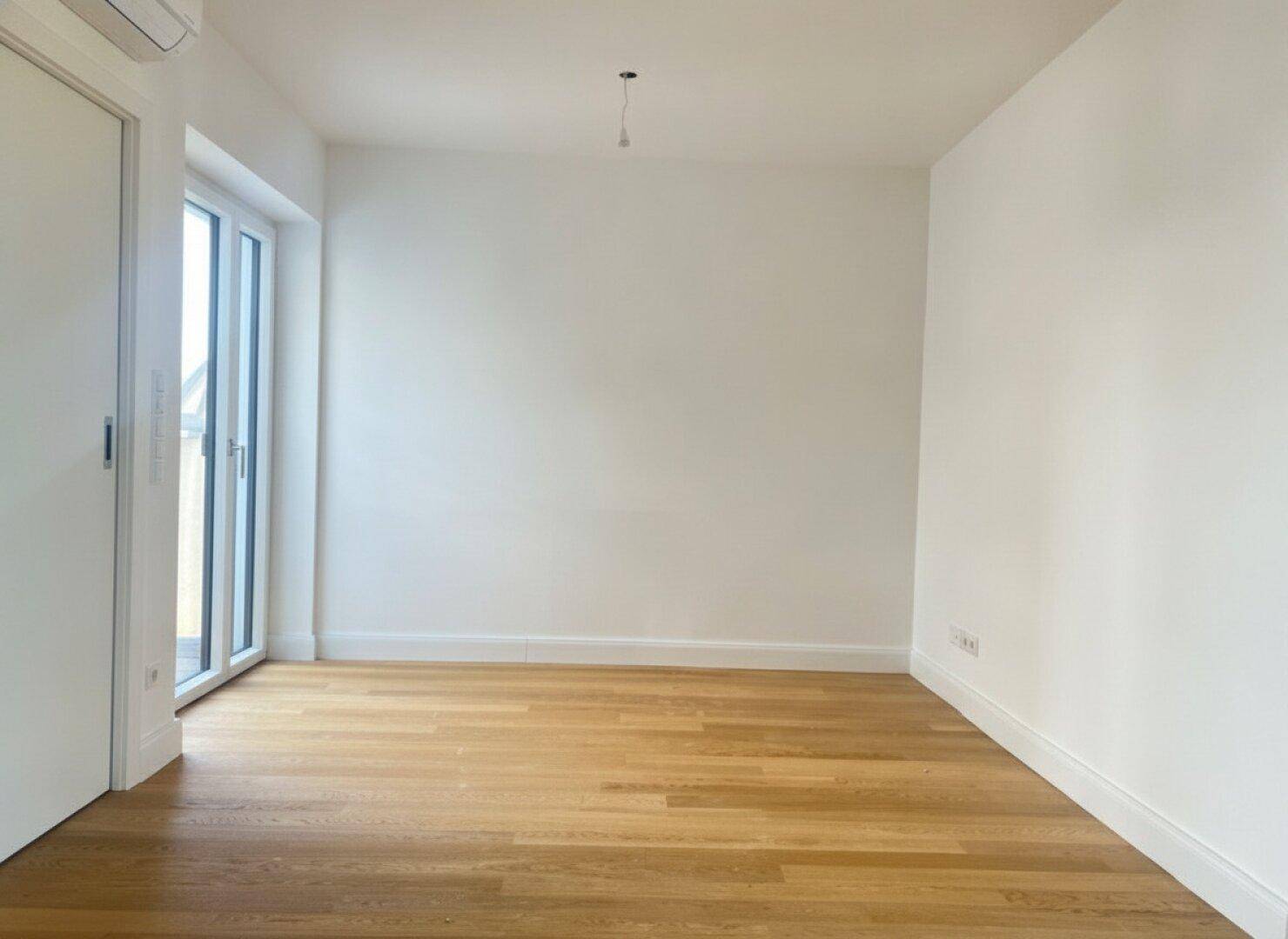 Heller Raum mit Holzboden und Zugang zu einem Balkon oder einer Terrasse, ideal als Essbereich.