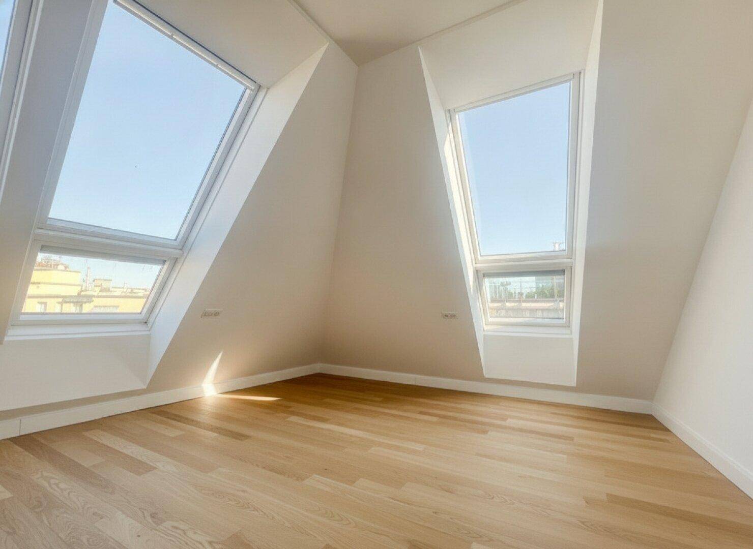 Lichtdurchflutetes Dachgeschosszimmer mit zwei großen Dachfenstern und Holzboden, ideal als Schlafzimmer.