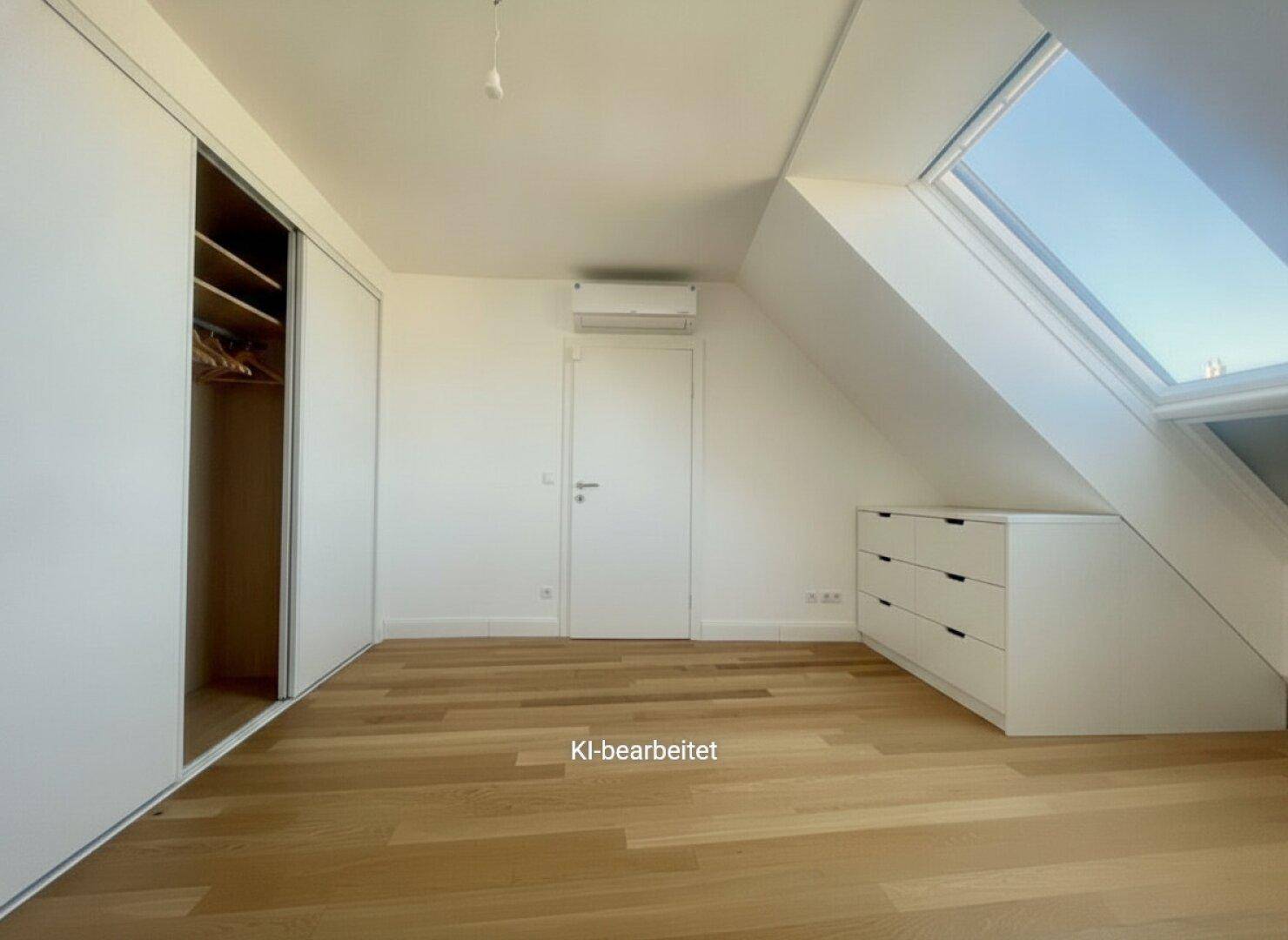 Geräumiges Schlafzimmer im Dachgeschoss mit Einbauschränken, Holzboden und Dachfenster.