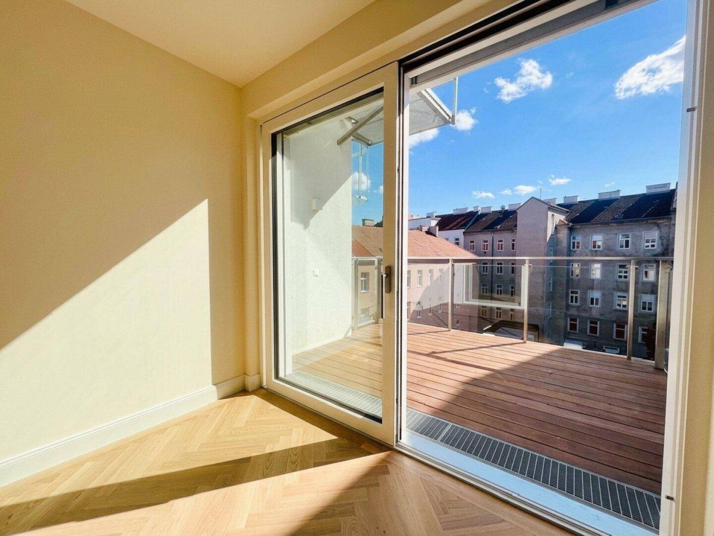 Heller Raum mit großen Schiebetüren zum Balkon und Fischgrätparkett.